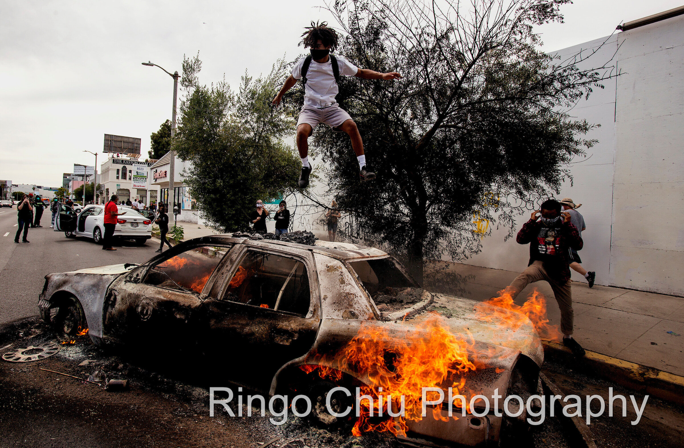  A man jumps on a burning police vehicle in Los Angeles, Saturday, May 30, 2020, during a protest over the death of George Floyd. Floyd died in Minneapolis police custody on Memorial Day. 