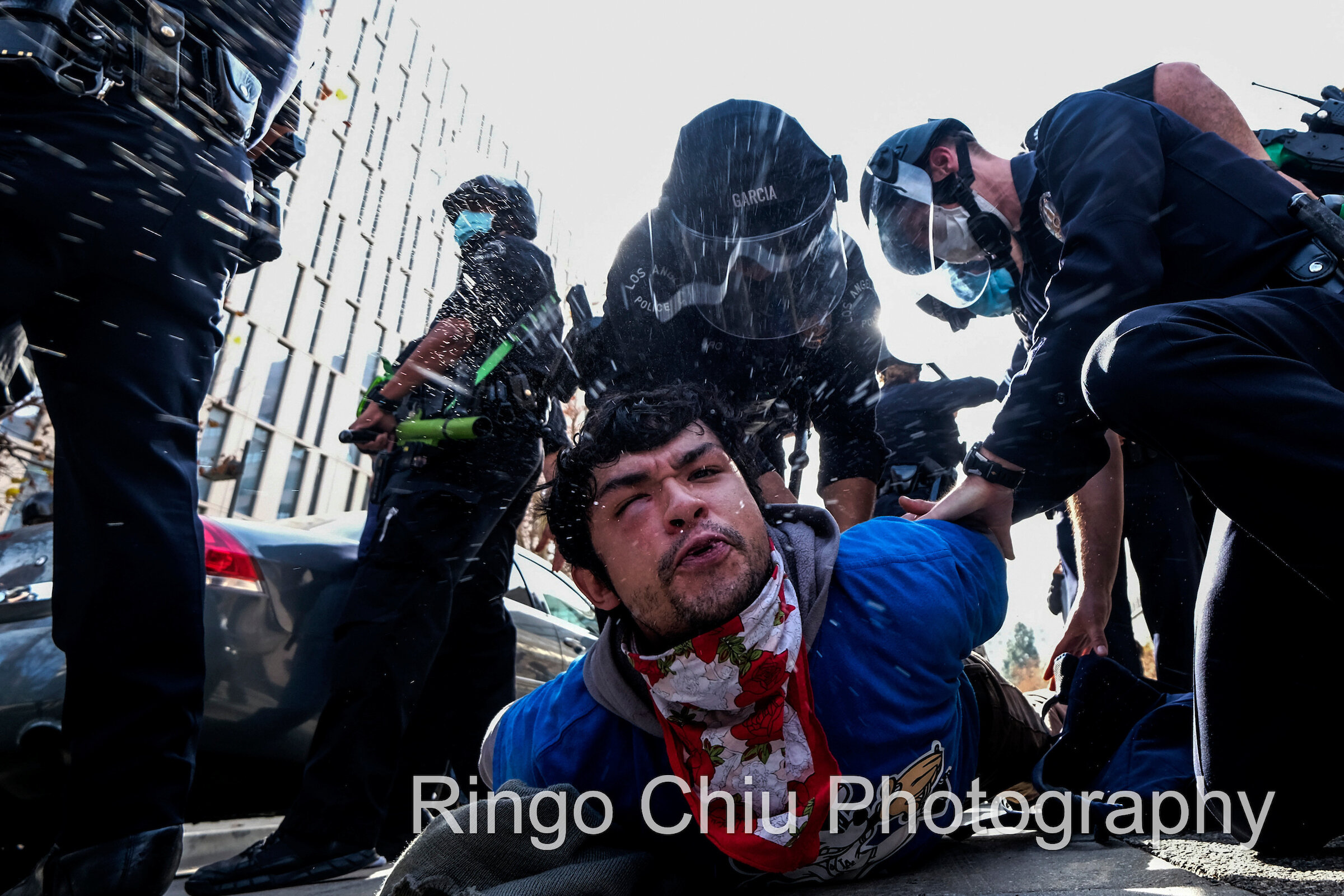  A protestor spits while being detained by police officers after a fight broke out during a protest in support of US President Donald Trump in Los Angeles on January 6, 2021. 