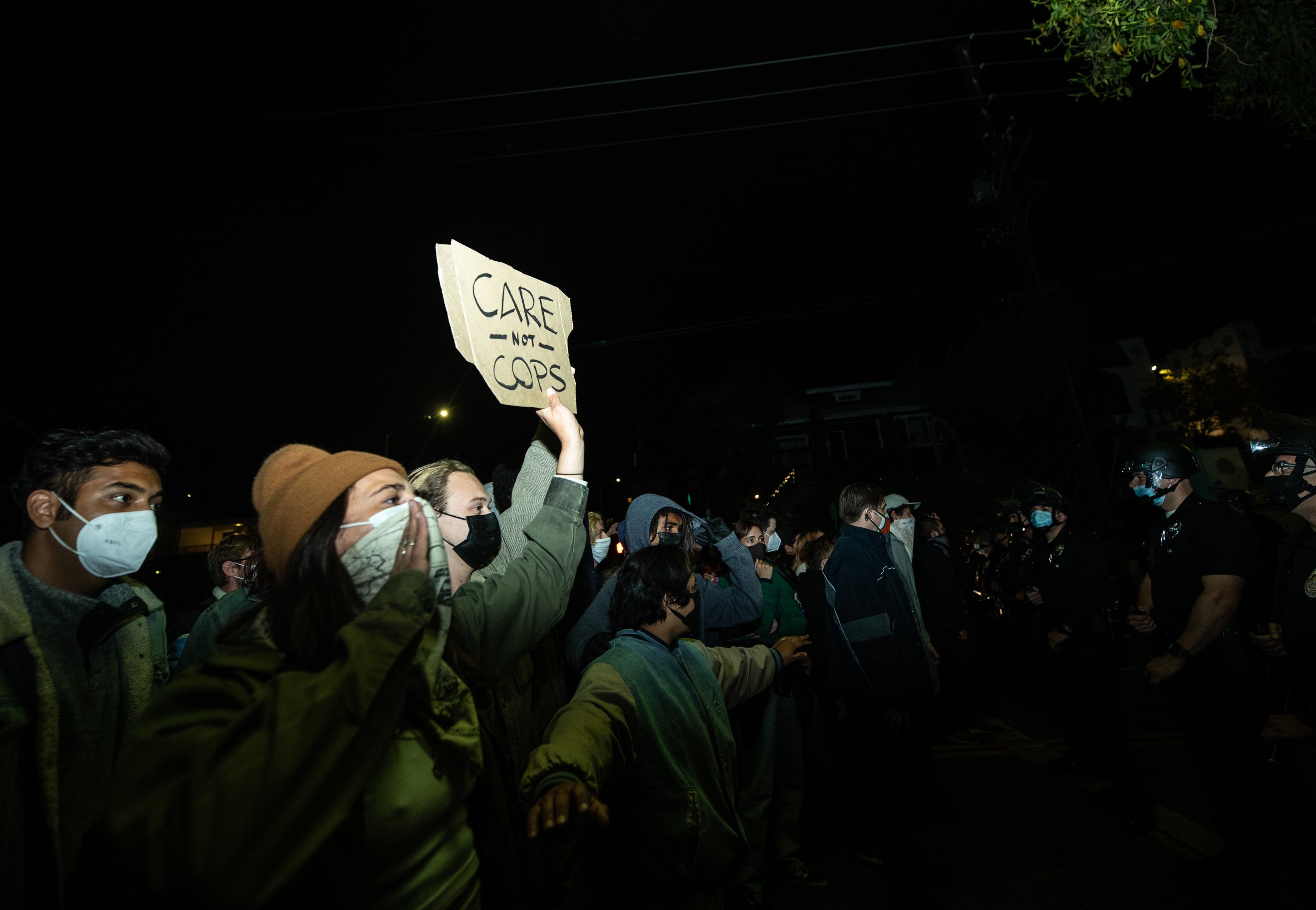  A protester holds up a sign March 24, 2021, near the Los Angeles Police Department skirmish line in an attempt to stop officers from removing an established homeless encampment at Echo Park Lake in the Echo Park neighborhood of Los Angeles. (Photo b