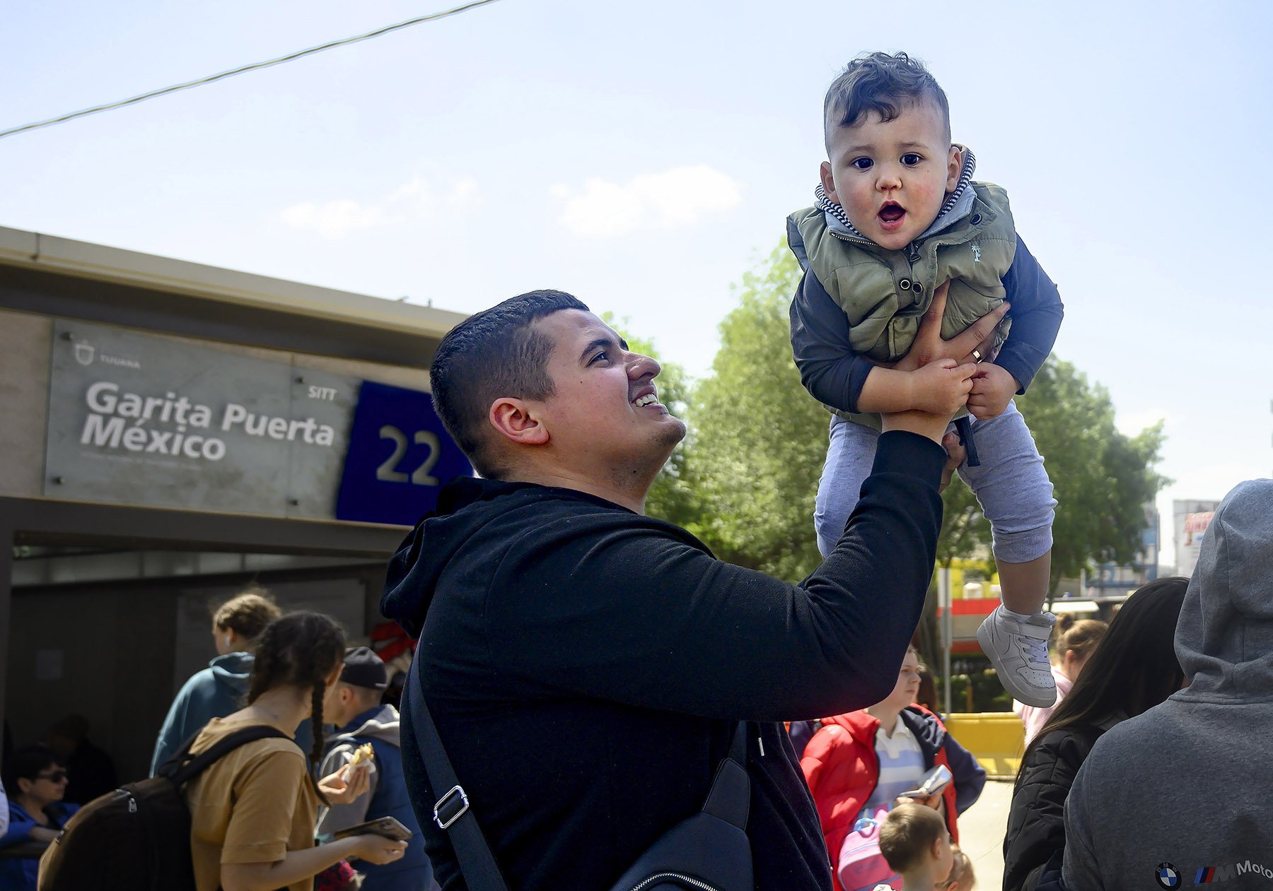  Artur Shkodinov tries to keep his 1-year-old son, Damir, entertained on Wednesday, March 30, 2022 while waiting  at the Tijuana border with his family for entry into the U.S. as refugees. For most people, it's a wait of at least a day now to get acr