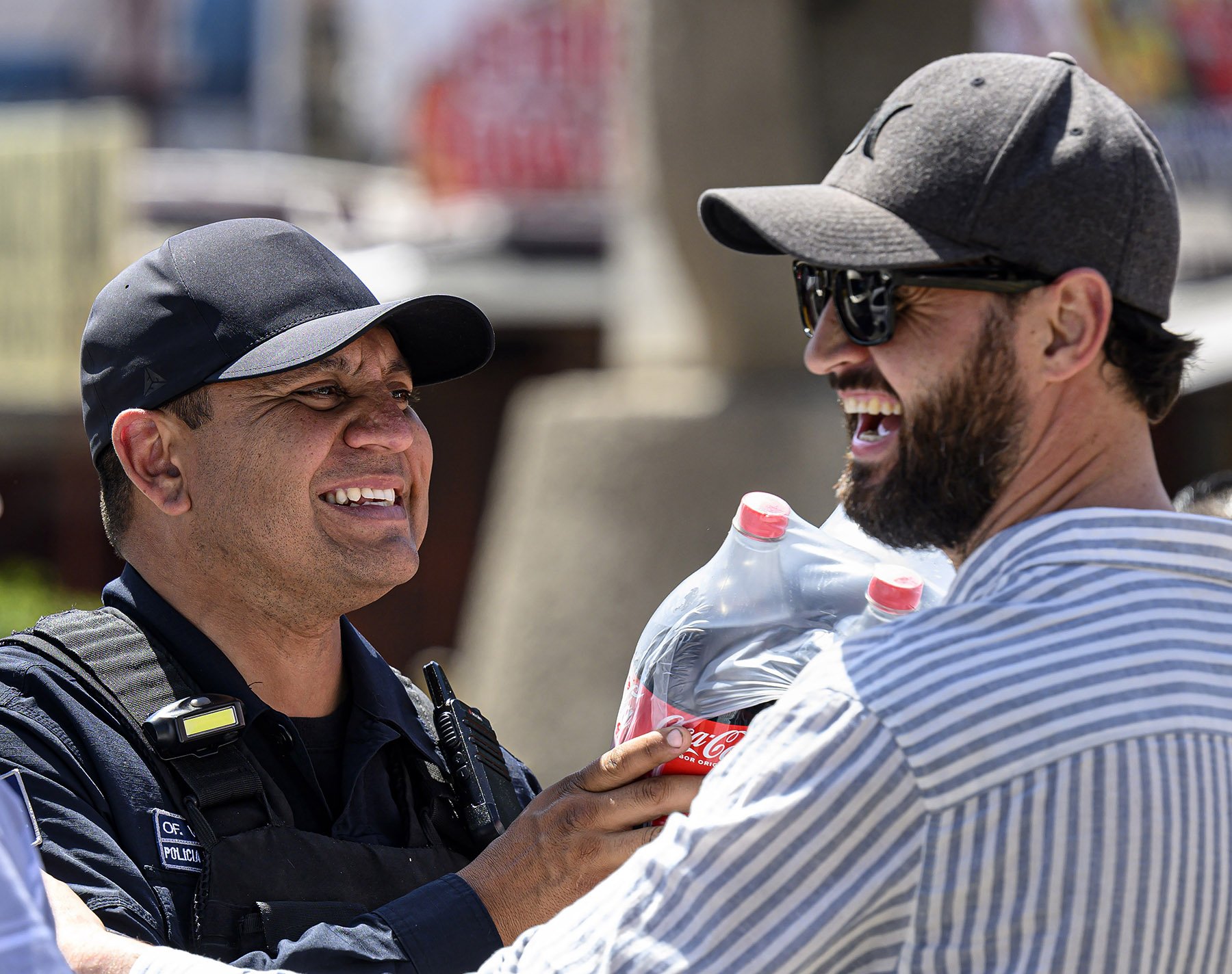  Ukrainian refugee Villi Mikhailov jokes with a Tijuana police officer while he and his twin brother Yan, help keep the asylum-seeking process running smoothly on Wednesday, March 30, 2022. Ukrainians helped with a waitlist for processing their fello
