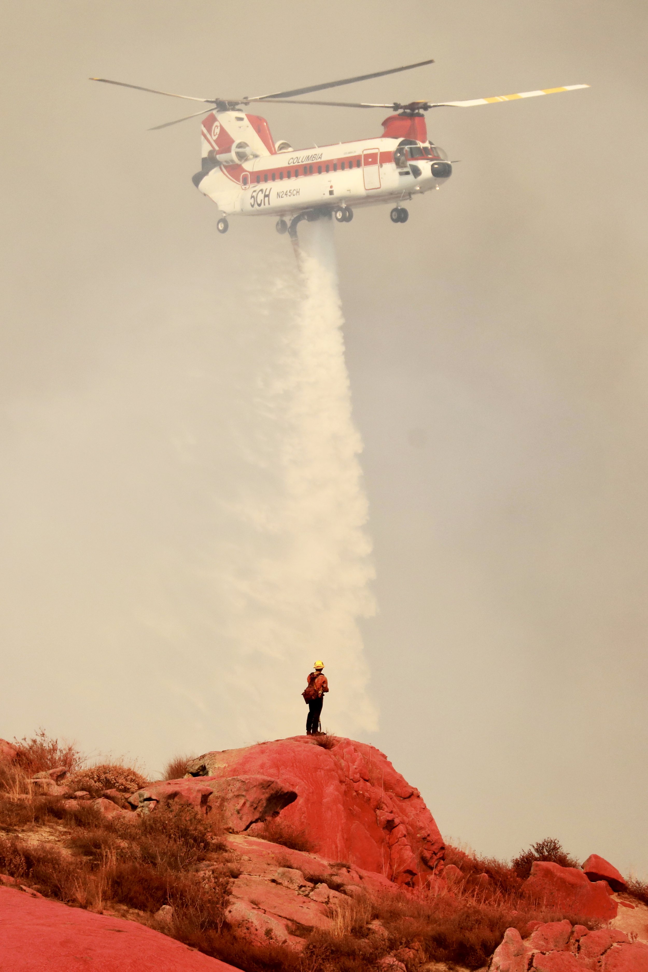  Water is dropped near a fireman standing on a Phos Chek painted hillside as the Fairview Fire burns near Hemet, California, U.S., September 6, 2022.  