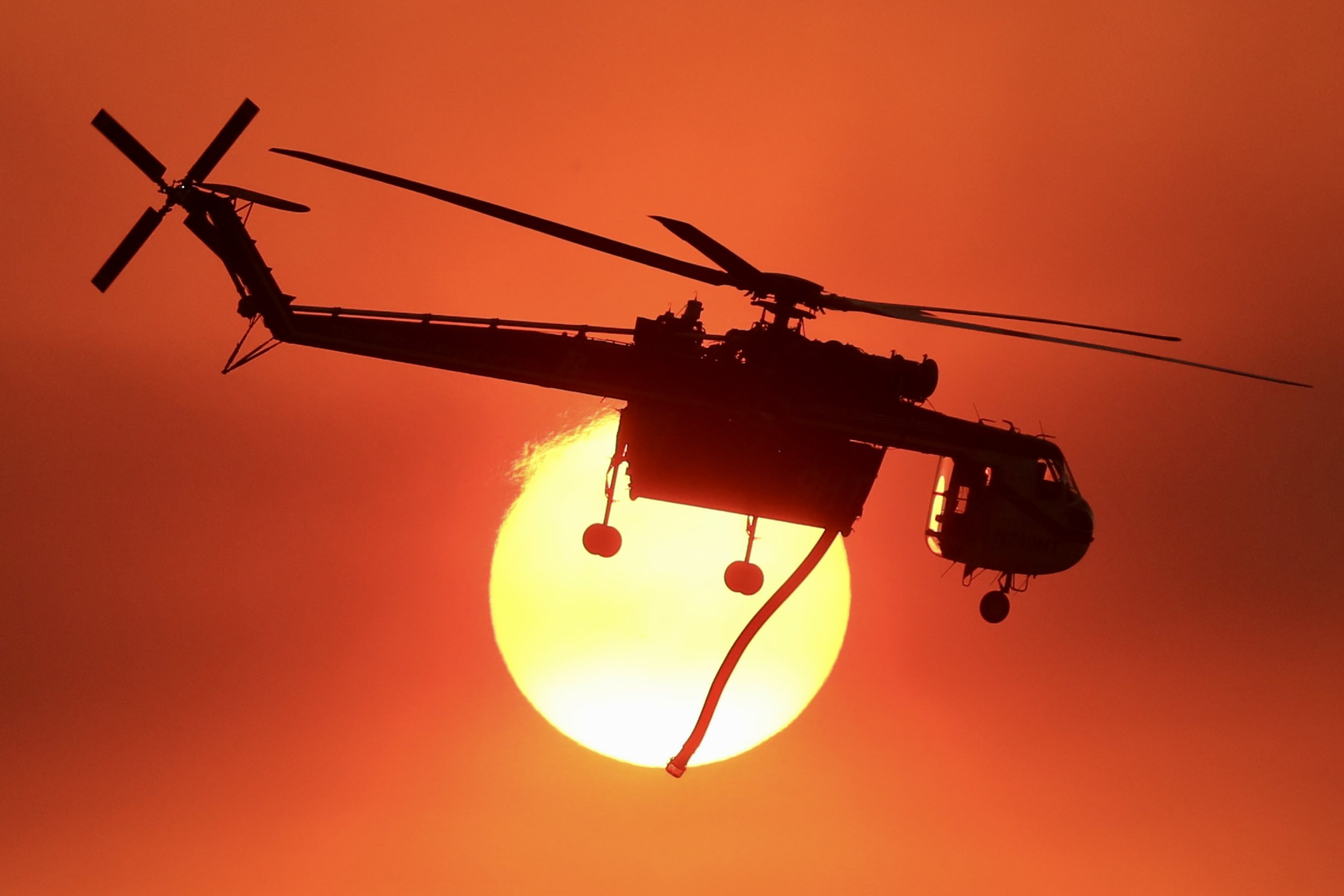  A CalFire helicopter passes the sunset over the Fairview Fire burning near Hemet, California, U.S., September 6, 2022.  