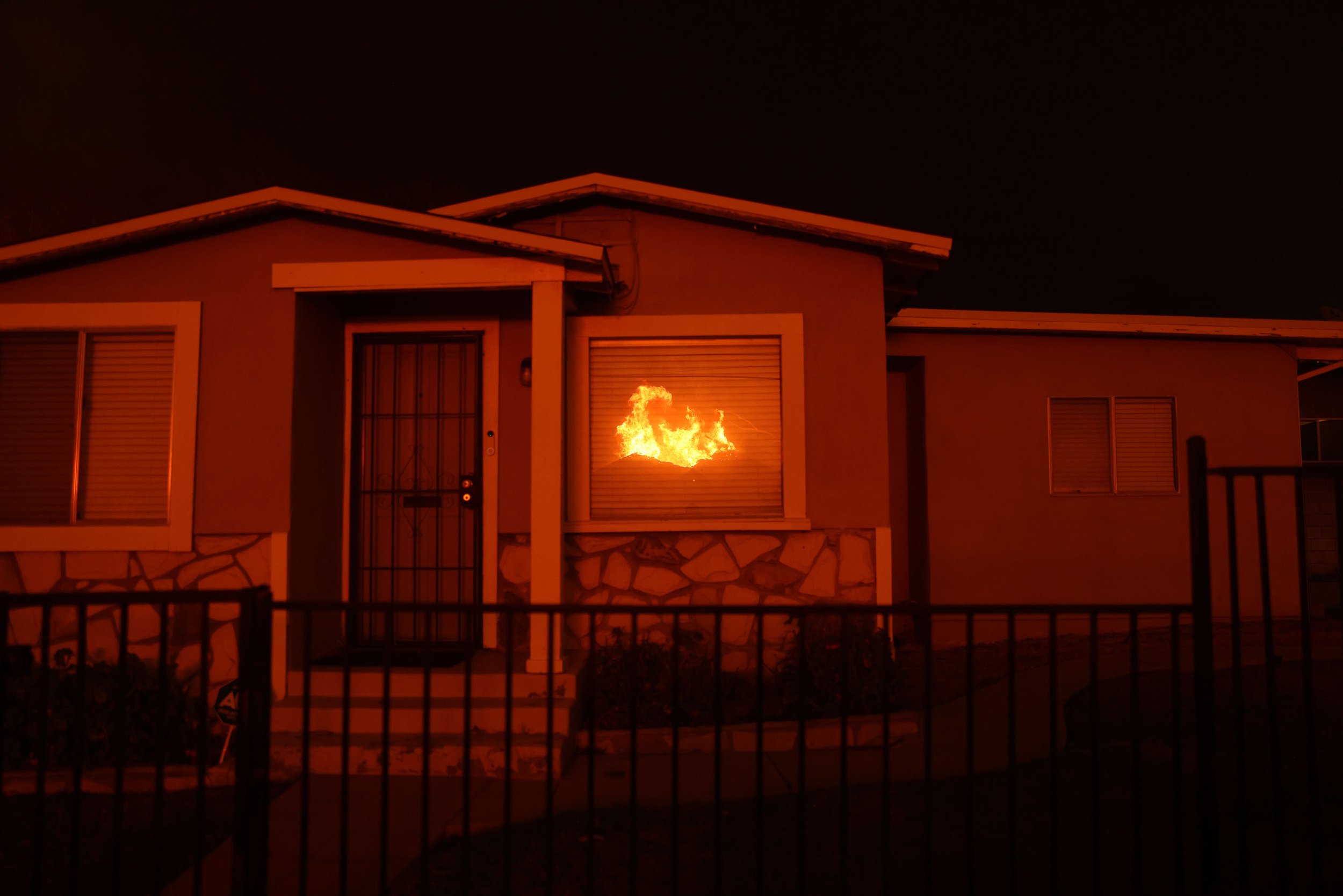  The reflection of a home during glows I another home window during the Eaton Fire in Altadena, California, January 8th, 2025. 