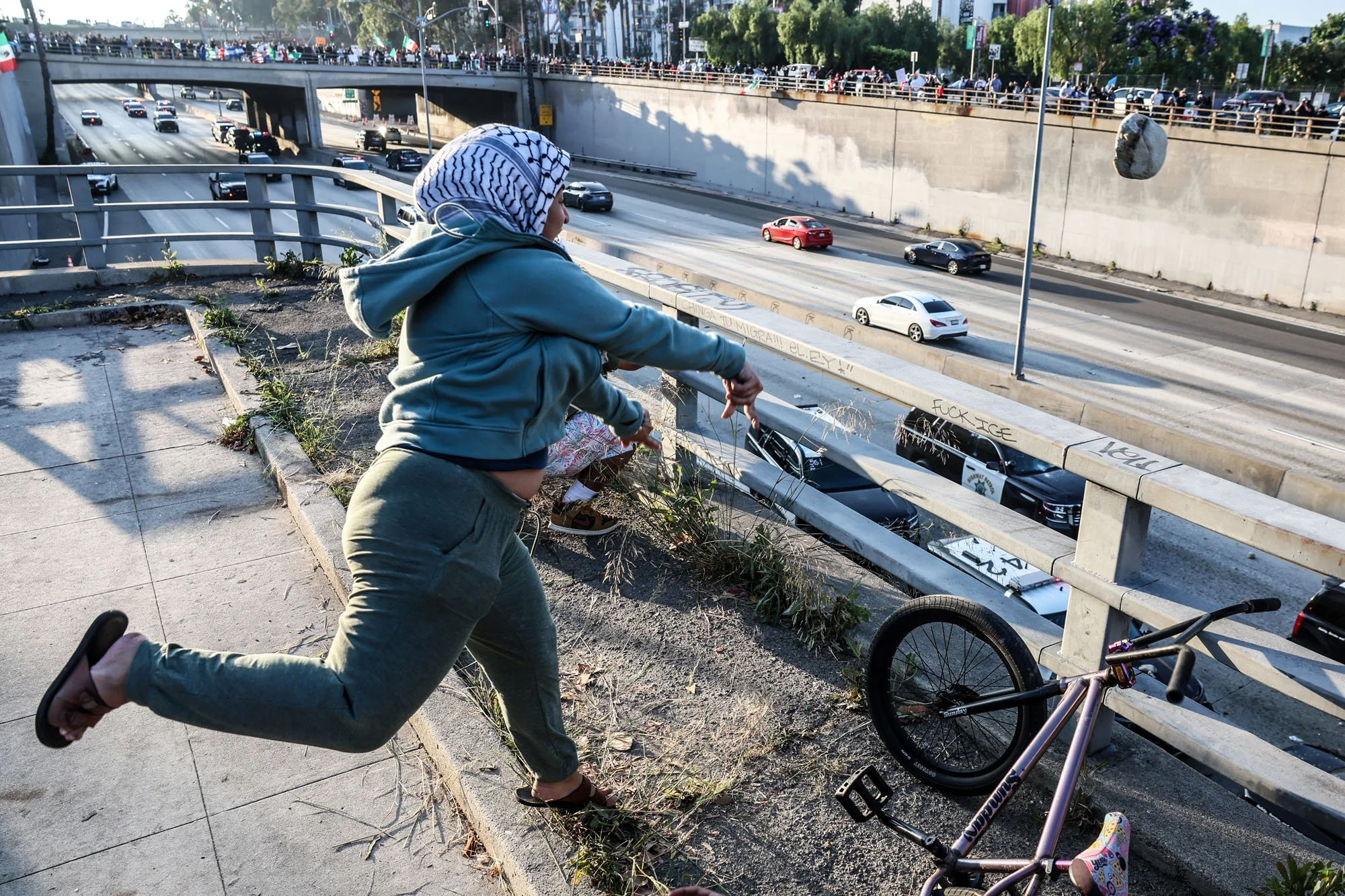  Los Angeles, CA, Sunday, June 8, 2025 - A protester lobs a large rock at CHP officers stationed on th 101 freeway below. Dozens tossed all sorts of objects, including Lime scooters at officer huddled below. 