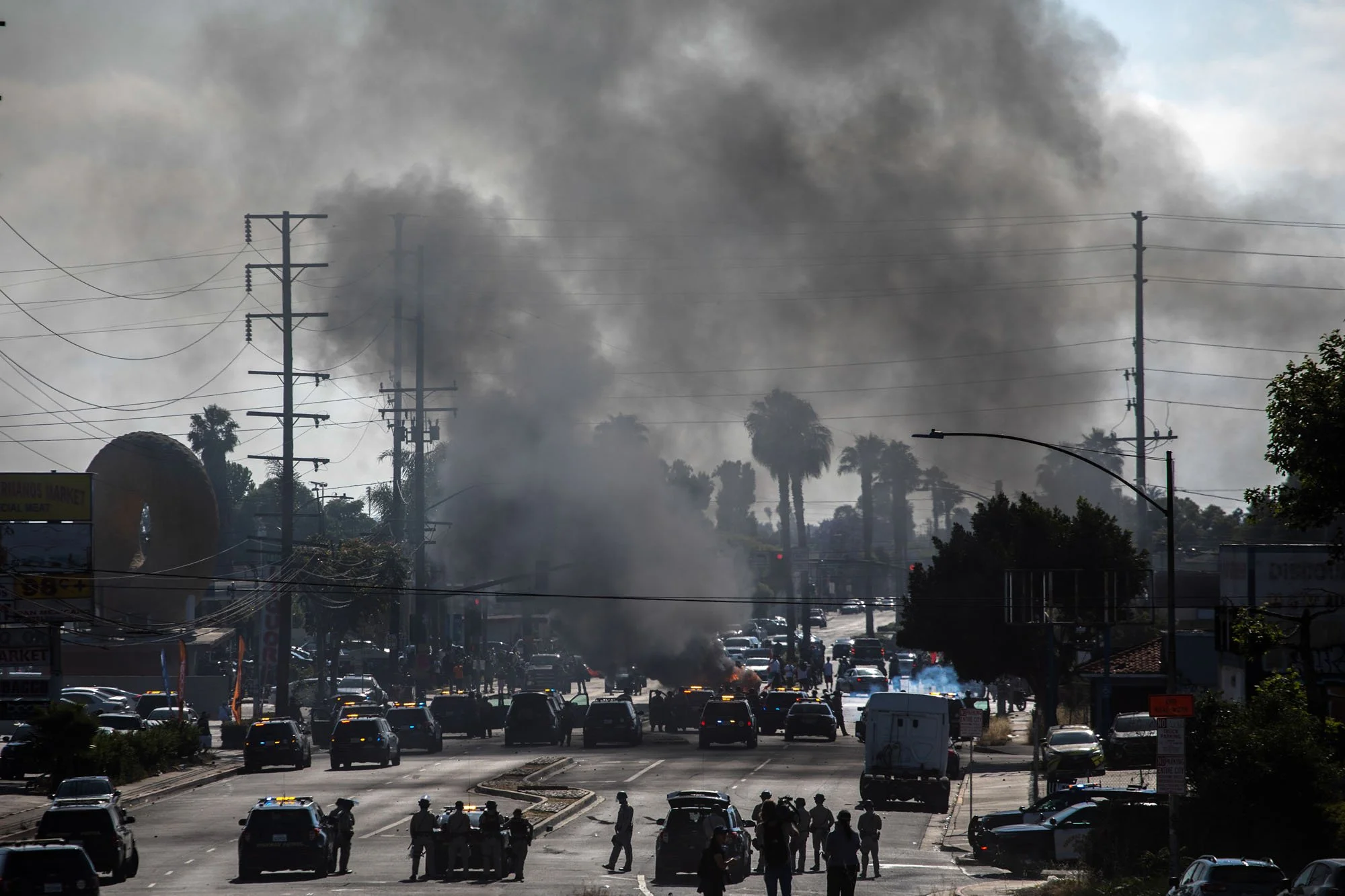  Smoke rises from a burning car as law enforcement officers confront protesters during a demonstration following federal immigration operations in the Compton neighborhood of Los Angeles on June 7, 2025. The protest erupted after Immigration and Cust
