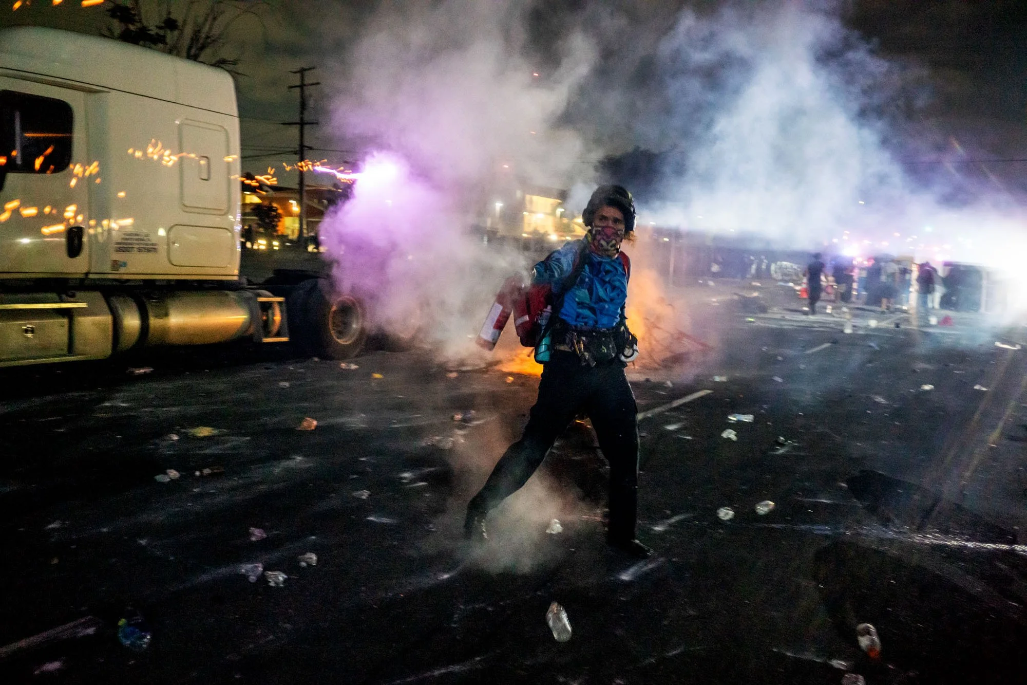  A protester carrying a fire extinguisher moves through smoke-filled streets during a nighttime demonstration following federal immigration operations in the Compton neighborhood of Los Angeles on June 7, 2025. The protest erupted after Immigration a