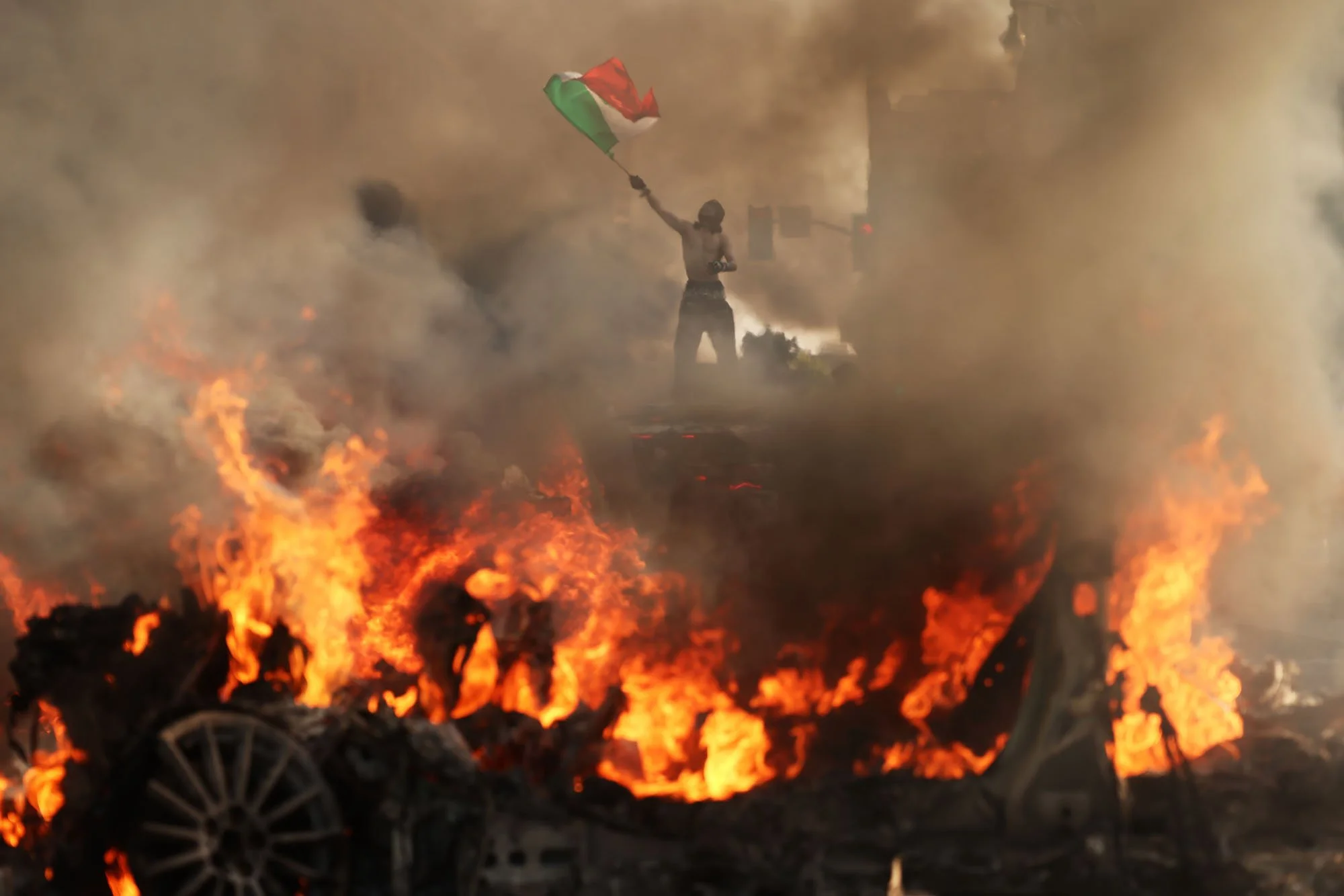  A man with a Mexican flag stan on one of five Waymos set on fire during a protest against federal immigration sweeps, in downtown Los Angeles, California. 