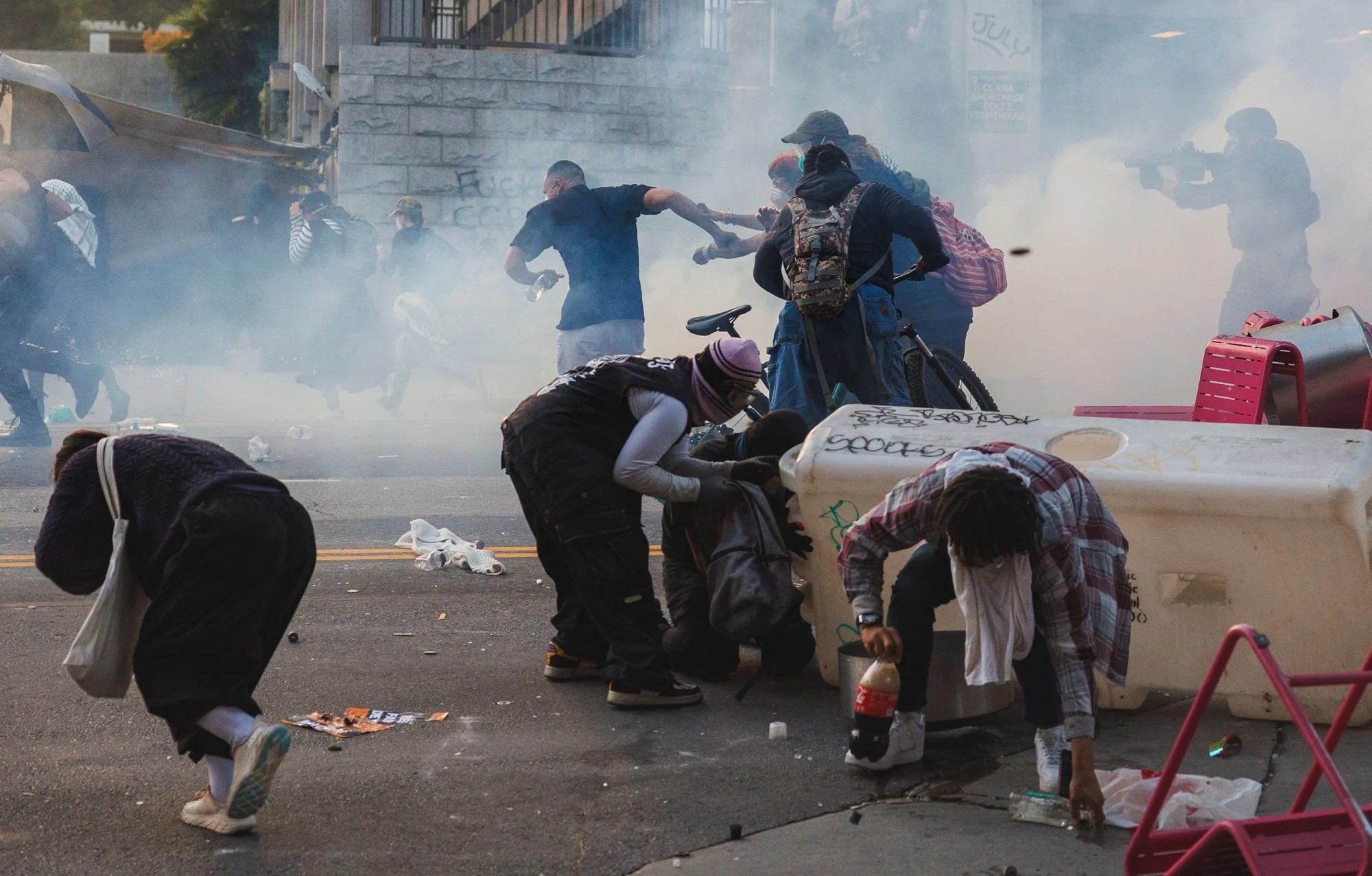  LOS ANGELES, CA - JUNE 8, 2025: Protesters run as Los Angeles Police officers shoot tear gas as they advance on demonstrators  who formed a makeshift barricade downtown  during a protest against immigration raids on June 8, 2025 in Los Angeles, Cali