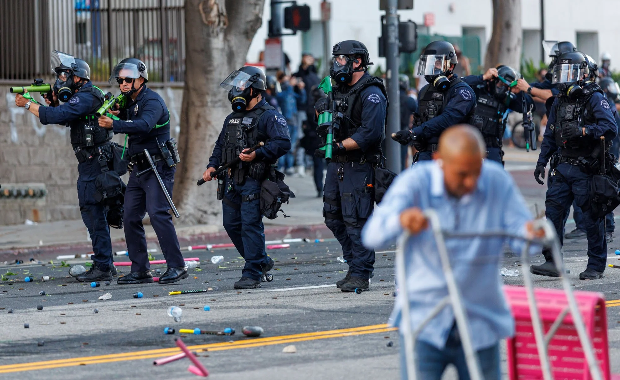  LOS ANGELES, CA - Alfredo Flores, 51, of Los Angeles, right, moves his walker onto the sidewalk as  Los Angeles Police officers shoot tear gas as they advance on demonstrators  who formed a makeshift barricade downtown  during a protest against immi