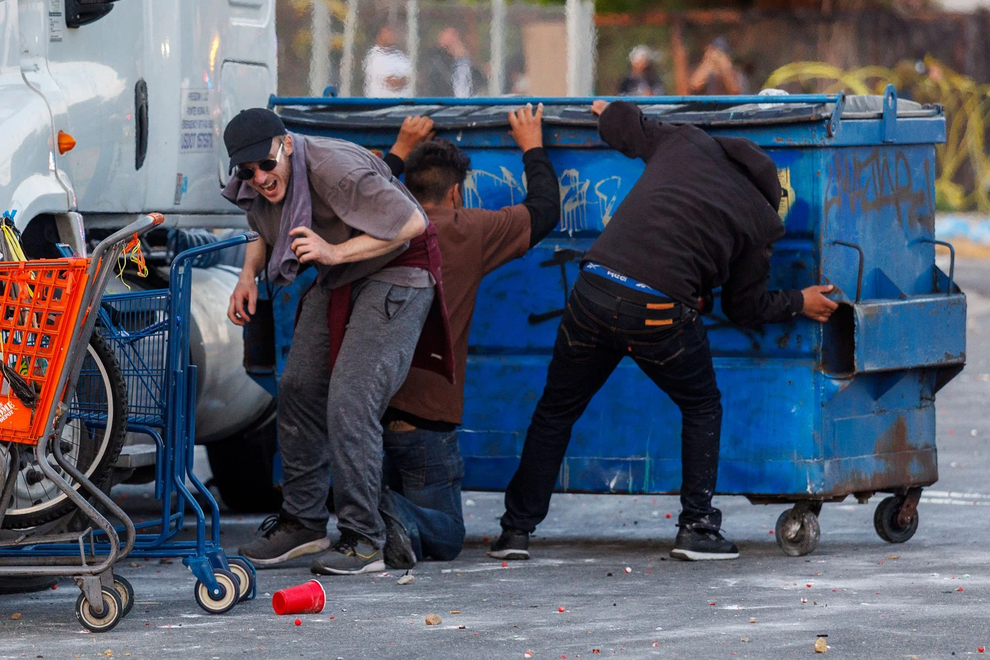  COMPTON, CA - Protester hide behind a dumpster as LA County Sheriff deputies shoot rubber projectiles during a protest against ICE raids on June 7, 2025 in Compton, California. 