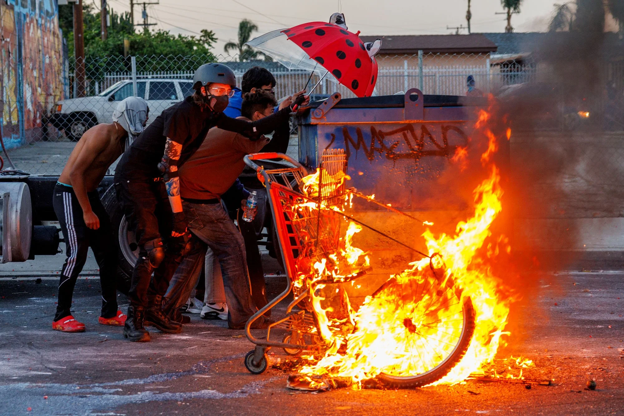  COMPTON, CA - Protester hide behind a dumpster after lighting a grocery cart on fire as LA County Sheriff deputies shoot rubber projectiles during a protest against ICE raids on June 7, 2025 in Compton, California. 