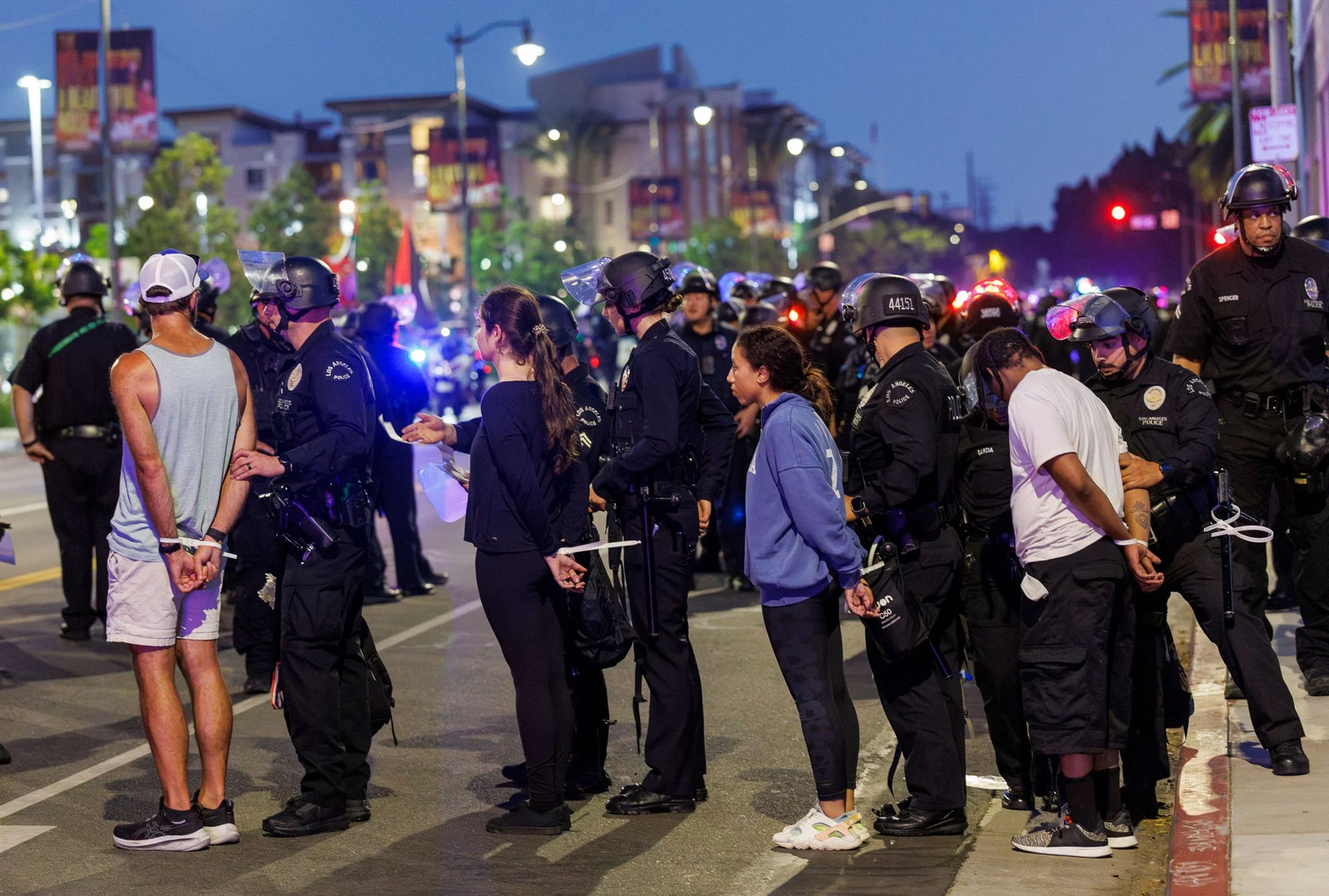  LOS ANGELES, CA - Protesters are lined up with zip ties on their wrists after being arrested for defying the 8PM curfew and for failing to disperse on Alameda Street during anti-immigration raid protests  on June 12, 2025 in Los Angeles, California.