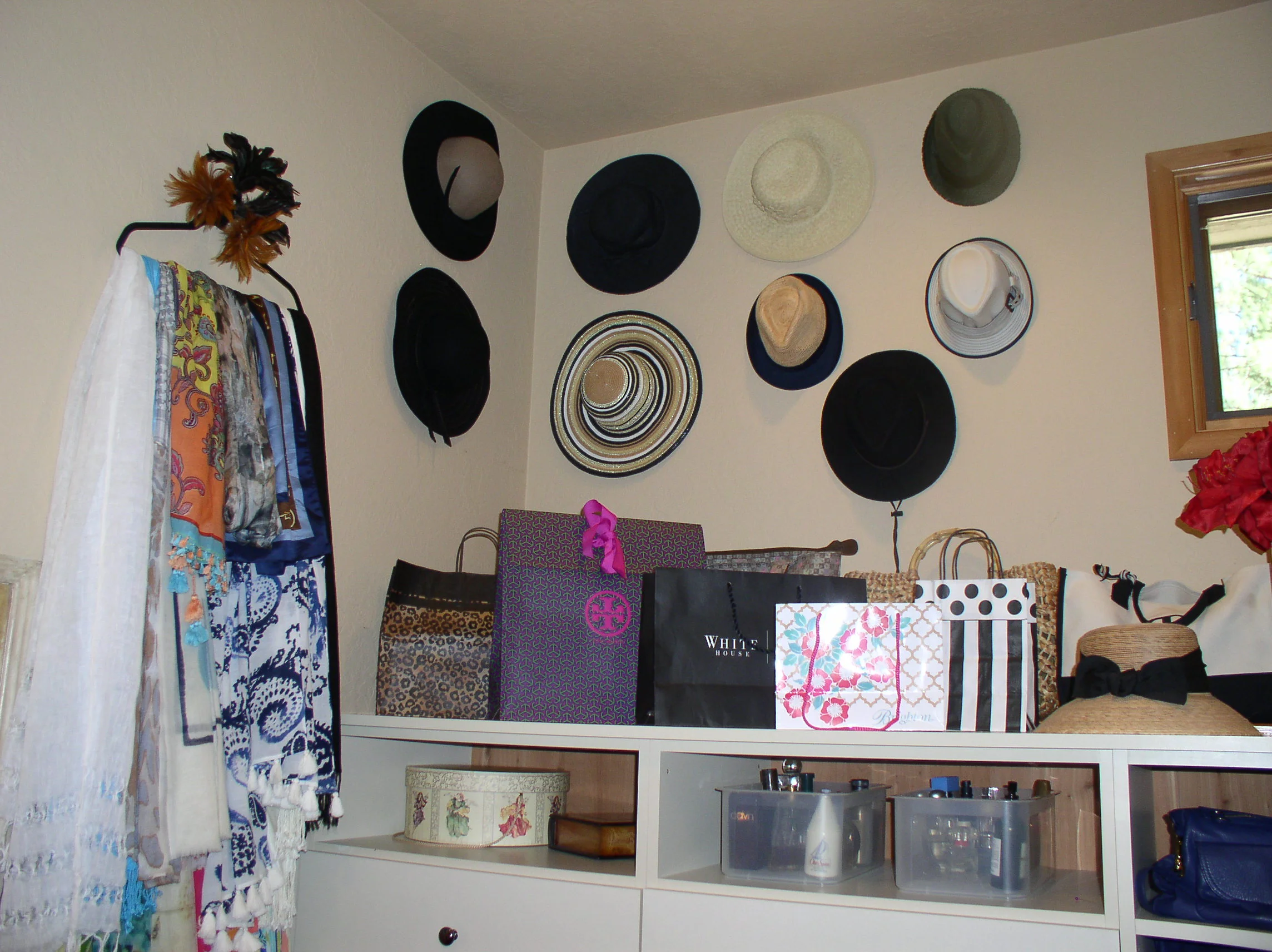 Hats on hooks and scarves hanging nearby. I used feather napkin rings from Pier One Import to decorate the hook they hang on. I have a few very pretty paper bags that are too pretty to through away.