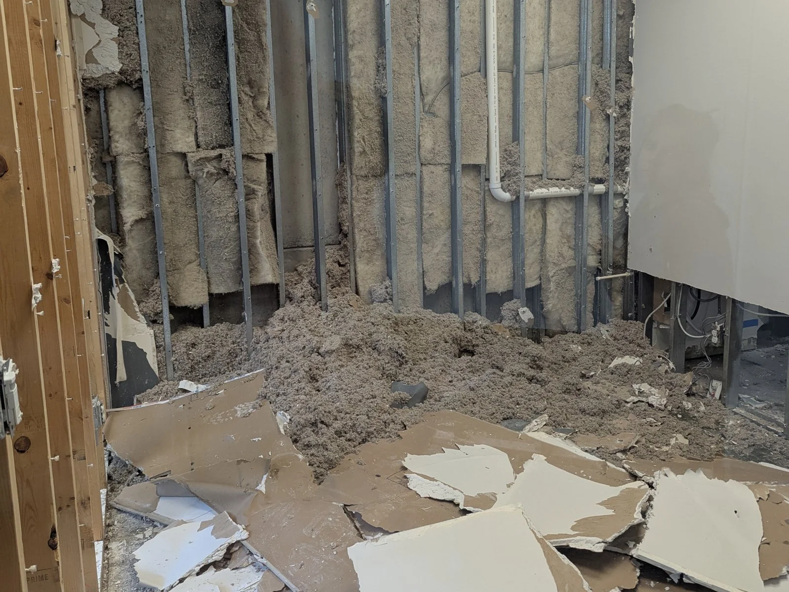 Flood damage at the L.I.H. Law office in Seattle in May 2025, with walls opened to the studs and drywall on the floor