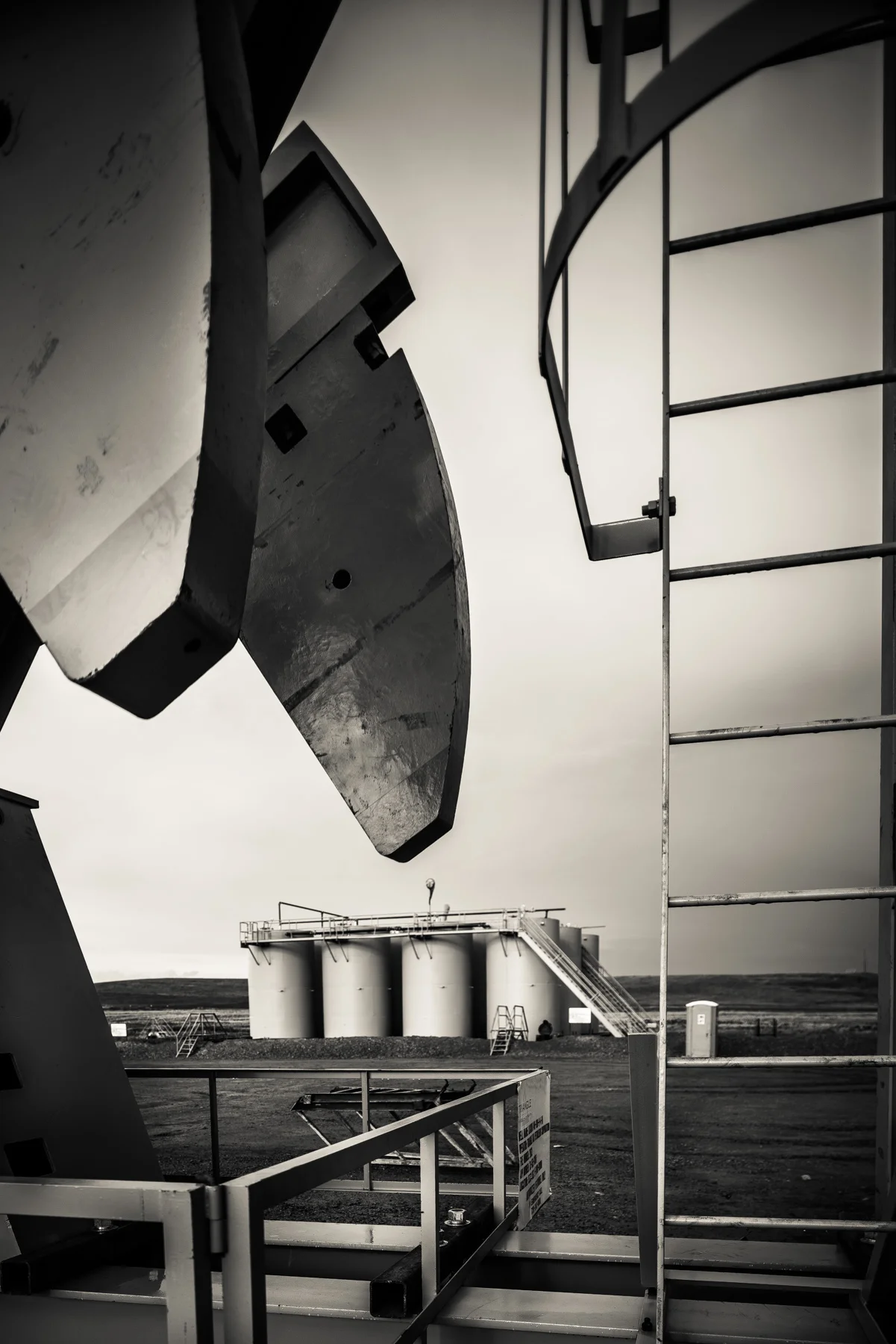 Pump jack and storage tanks at a pump site. Tanks always come in groups of threes: two for water, one for oil. 