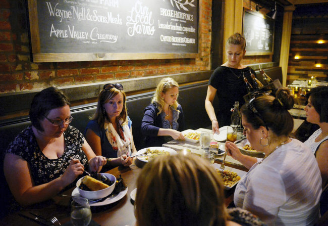 Kellie Wivell, Kelly Stahlman, Mindy Ott, Laci Wildasin, Kara Olewiler and Jessica Daniels begin eating their meal at Tutoni's Restaurant as server Sarah Grim sets down a fresh plate. Tutoni's Restaurant, which serves Mediterranean-inspired food made with locally sourced ingredients, operates on a seasonal menu. (Chris Dunn — FlipSide)