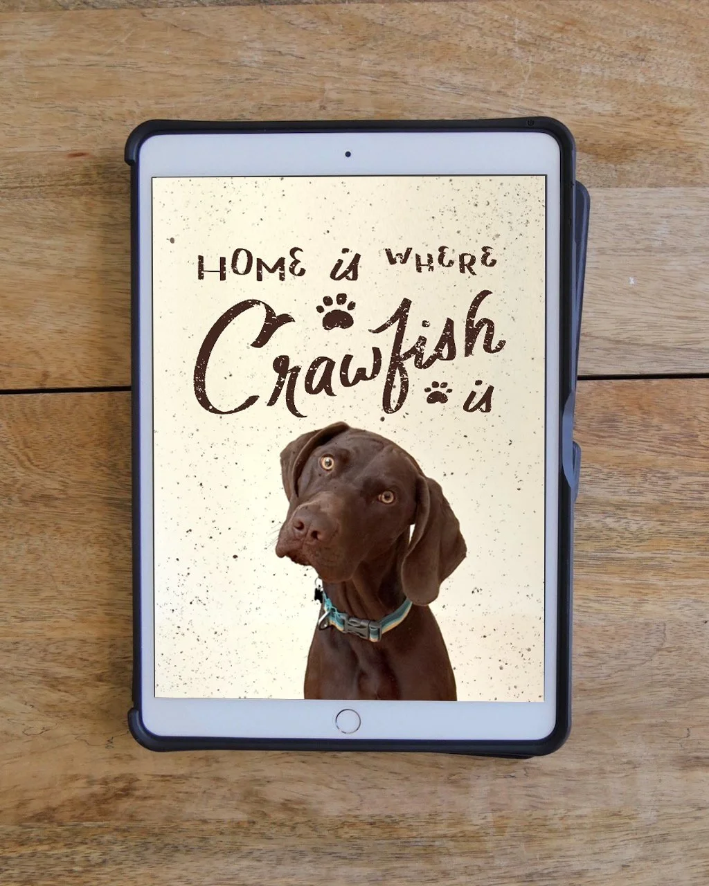 Tablet screen displaying a digital drawing with the handlettering 'Home is where Crawfish is' and an image of a brown puppy with big ears and a collar.