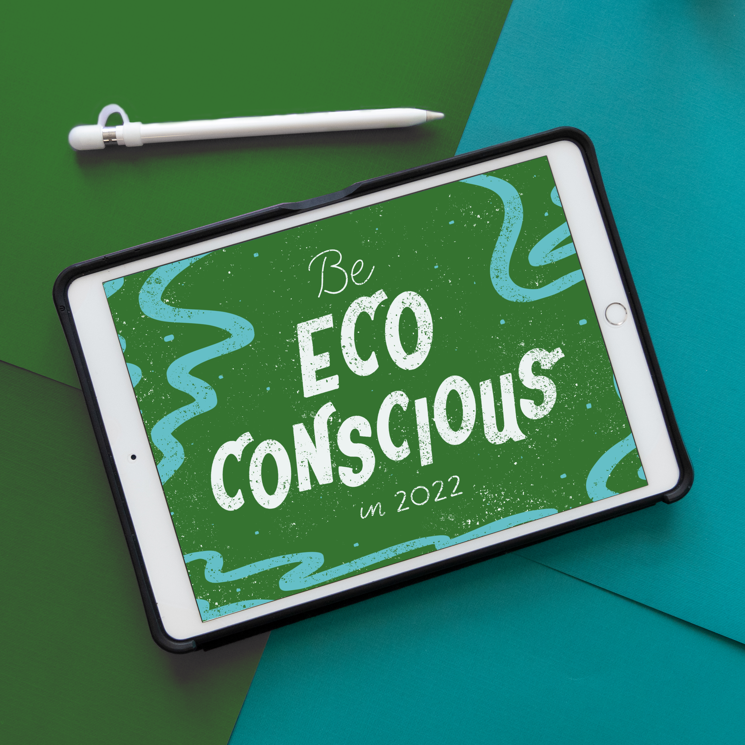 Tablet screen displaying a digital drawing with the hand lettering "Be Eco Conscious in 2022," decorated with blue squiggly lines and white speckles, placed on a background of blue and green paper with a white Apple Pencil beside it.