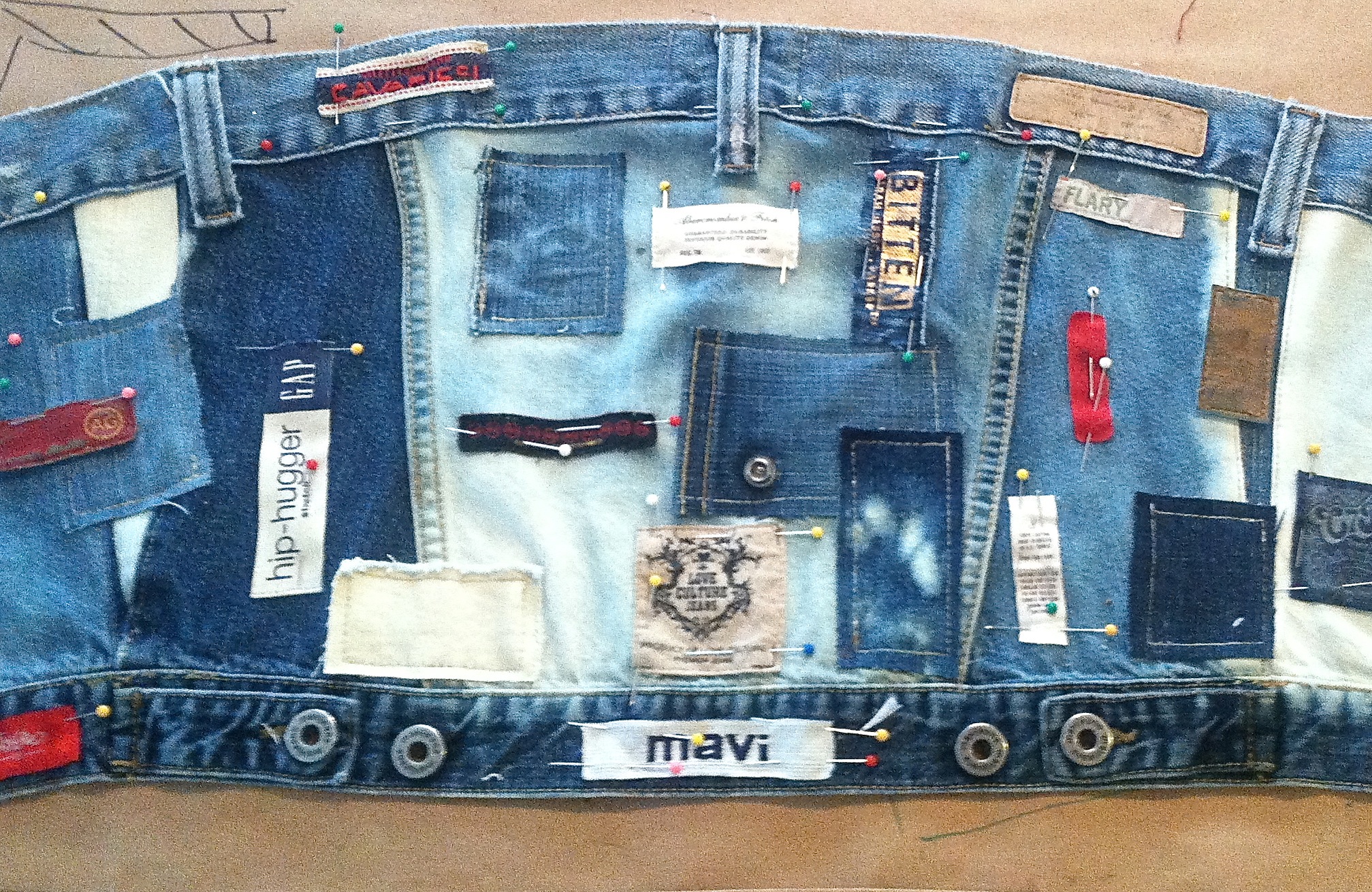 This started out as the back of a jean jacket, and I altered the shape, bleached sections, but left the bottom band intact. The top band is a waistband from a pair of jeans, and I used the beltloops also. As I ripped apart jeans for the skirt section, I fell in love with all the labels, so decided to sew them all over the bustier.