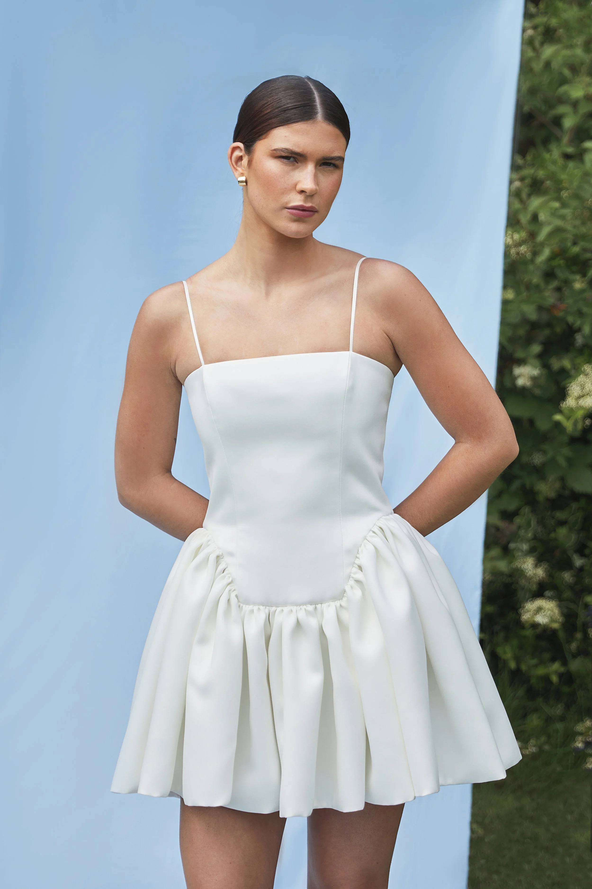 Where maximal gathers and volume meets minimal necklines and detailing. The Delphine Mini features an extended dropped waist bodice, cut to highlight the feminine form and mini gathered skirt. Constructed in buttery soft duchess satin, with the inter
