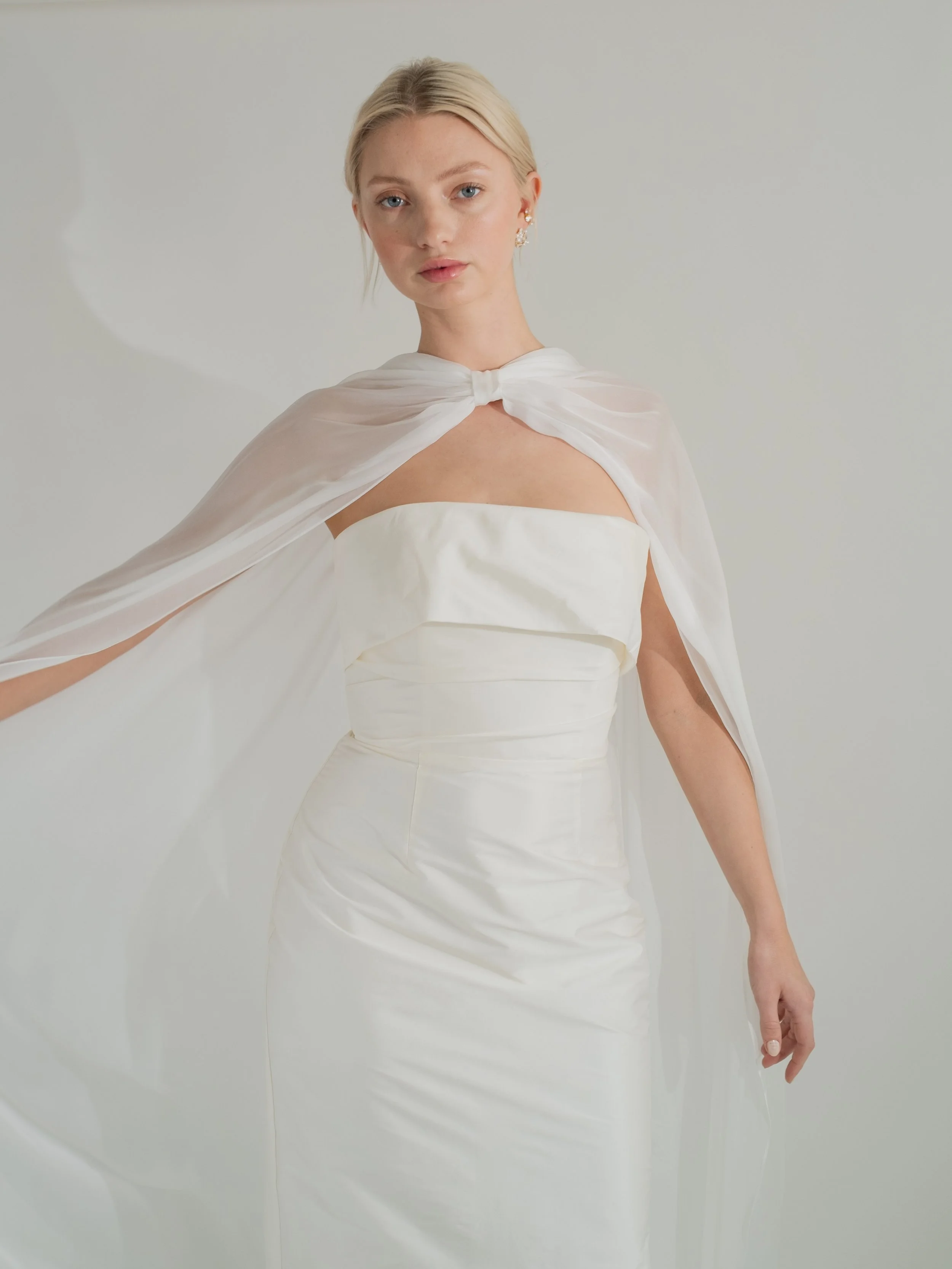 An elevated neck scarf made in silk chiffon with tiny rolled hems, the Sian scarf features pleated gathers at the neck with soft bow detailing. For an effortlessly cool look, this piece is designed to be worn on the shoulders rather down the back giv