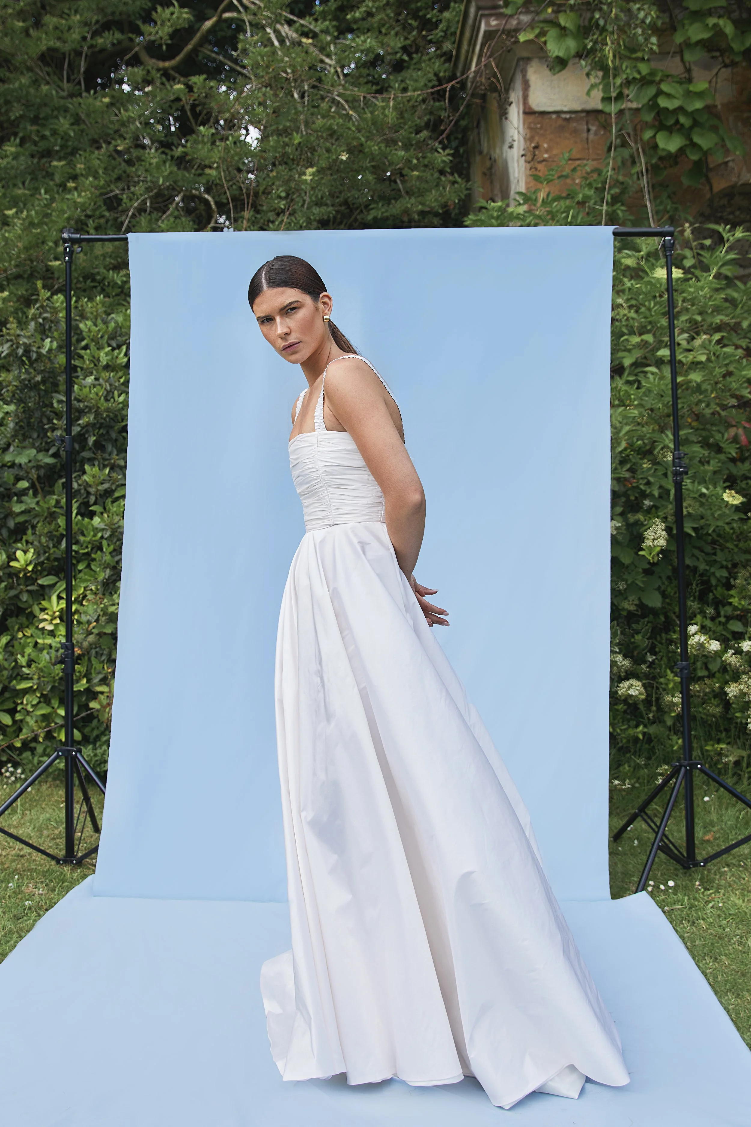 Tiffany wedding dress by Jessica Bennett. Featuring hand-pleated taffeta sits over an internal boned corset giving structure and support. Paired with full circular skirt and pockets. 