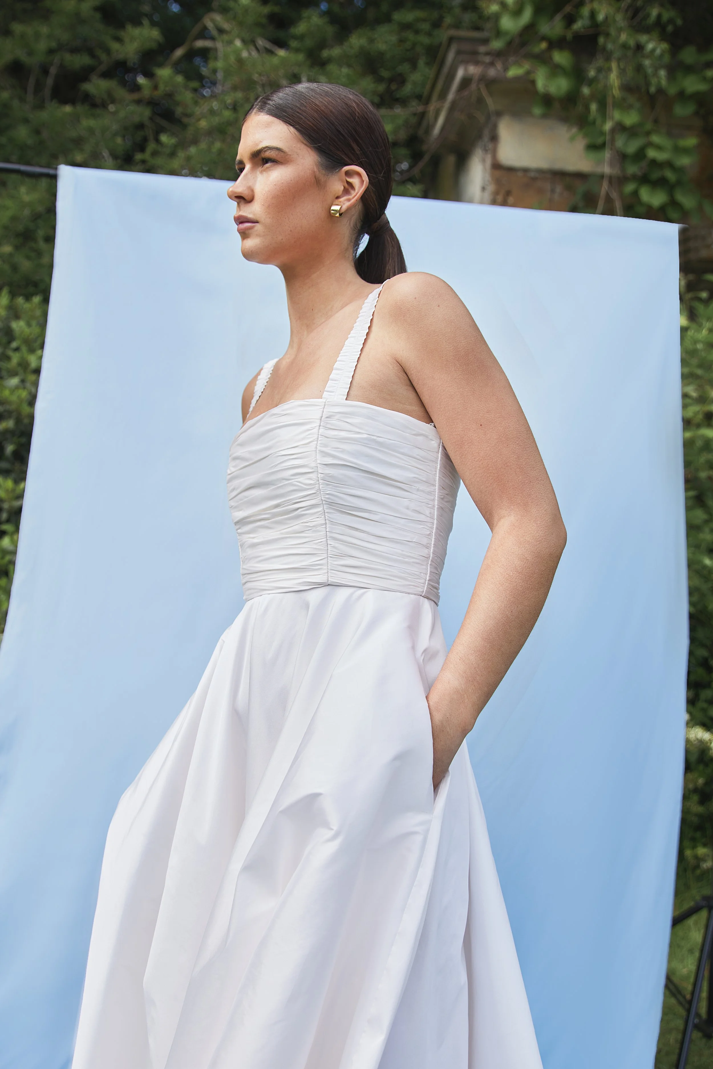 Tiffany wedding dress by Jessica Bennett. Featuring hand-pleated taffeta sits over an internal boned corset giving structure and support. Paired with full circular skirt and pockets. 