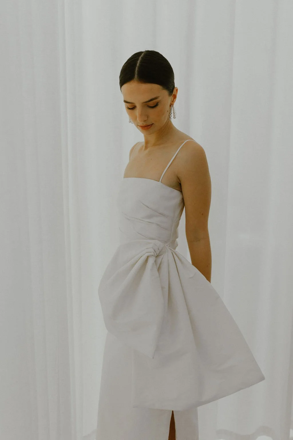 The perfect reception or civil ceremony piece. The She Midi features side waist pleating, an above ankle hemline and side split. Style alone or layer with our sleeve / bow additions for an interchangeable look. Fastens with concealed side zip allowin