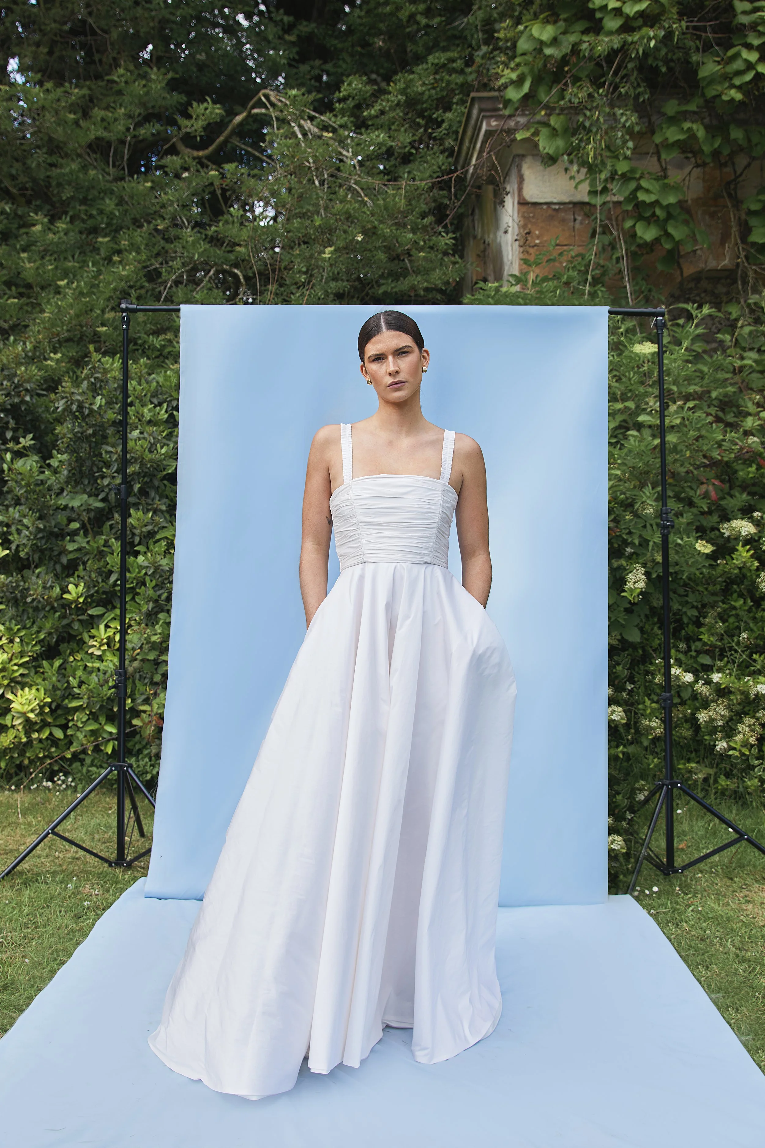 Tiffany wedding dress by Jessica Bennett. Featuring hand-pleated taffeta sits over an internal boned corset giving structure and support. Paired with full circular skirt and pockets. 