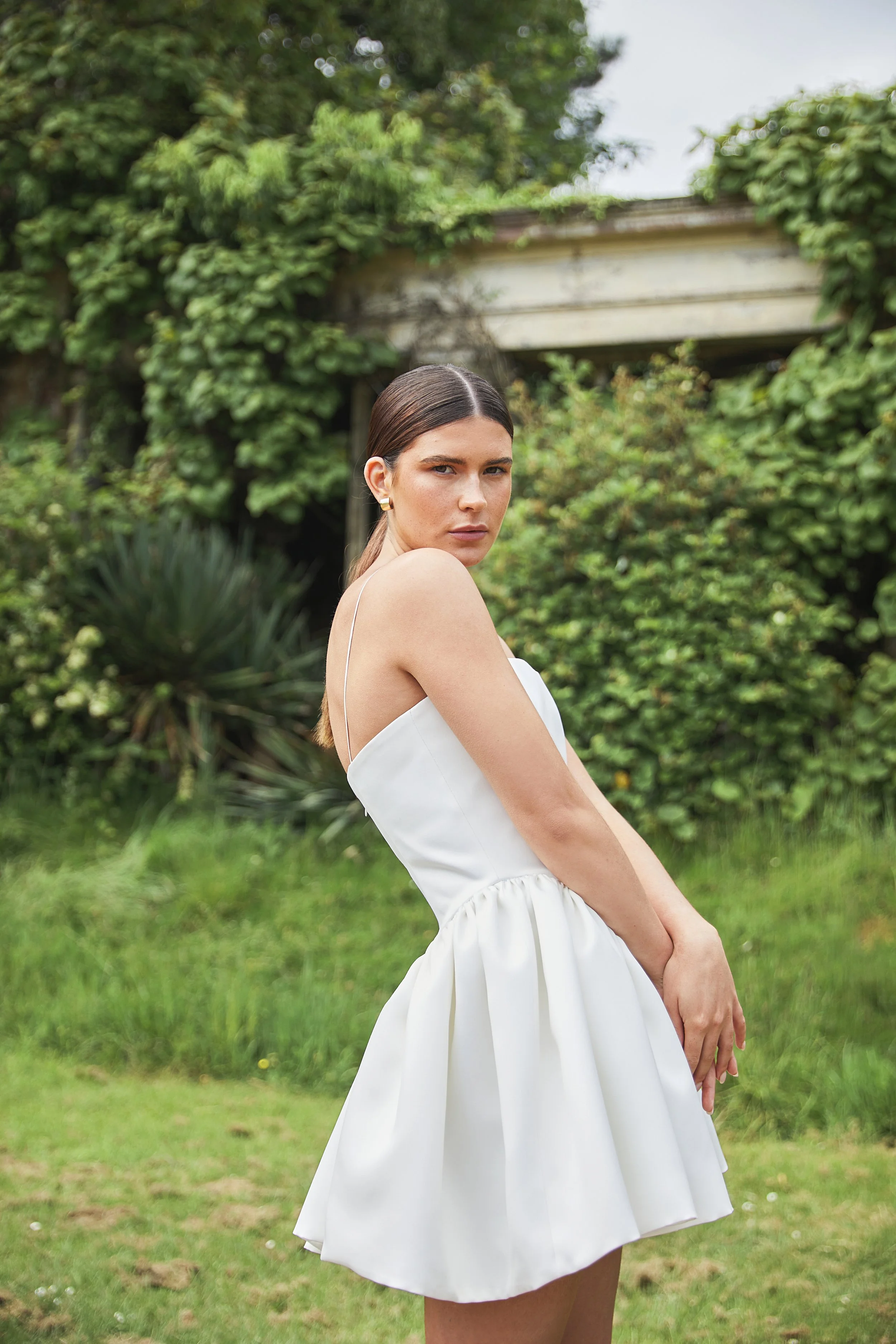 Where maximal gathers and volume meets minimal necklines and detailing. The Delphine Mini features an extended dropped waist bodice, cut to highlight the feminine form and mini gathered skirt. Constructed in buttery soft duchess satin, with the inter
