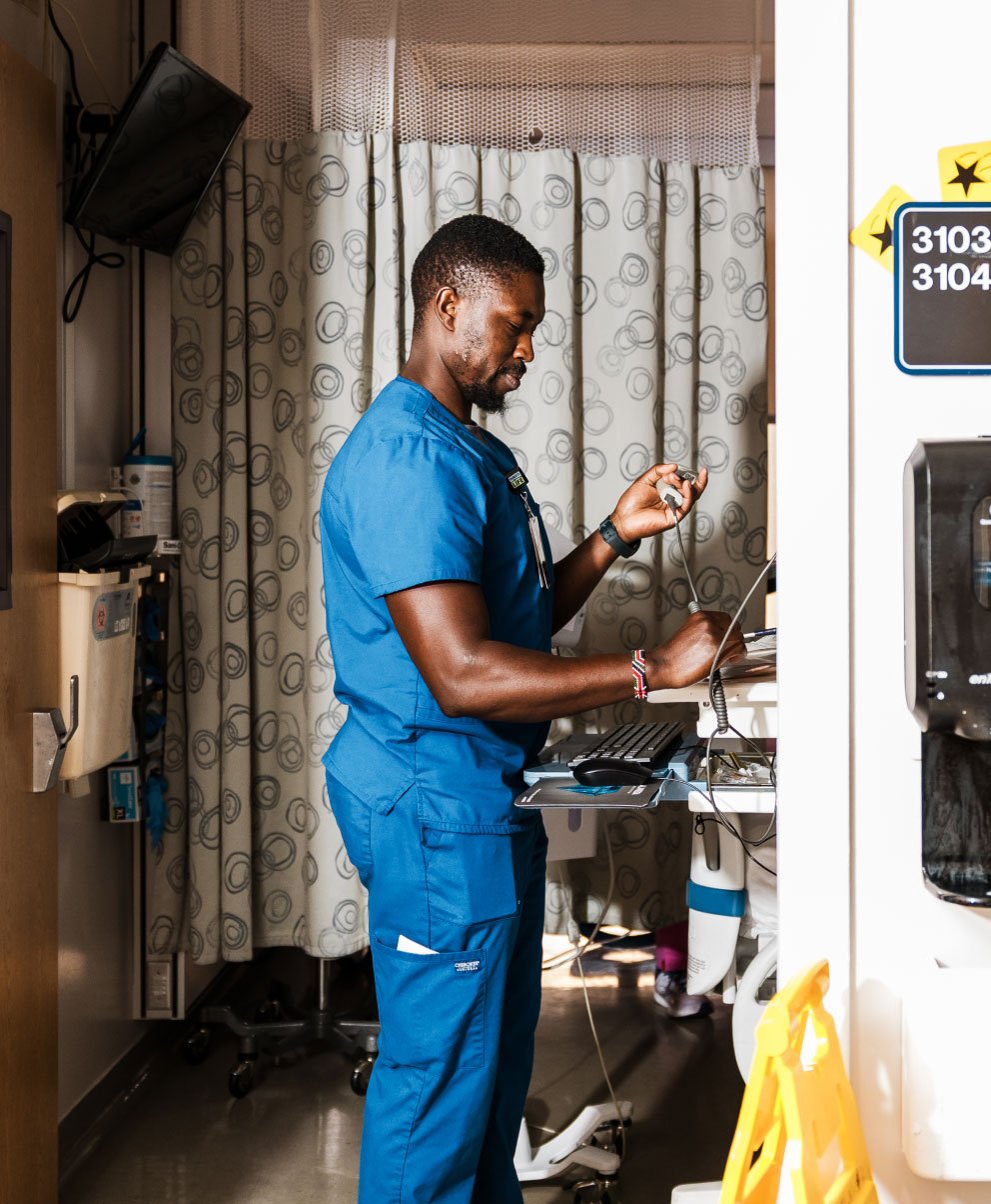 An environmental lifestyle photograph capturing a medical professional interacting with care assets inside a modern hospital examination room. Photography by Carolyn Fong for Flight Design Co.