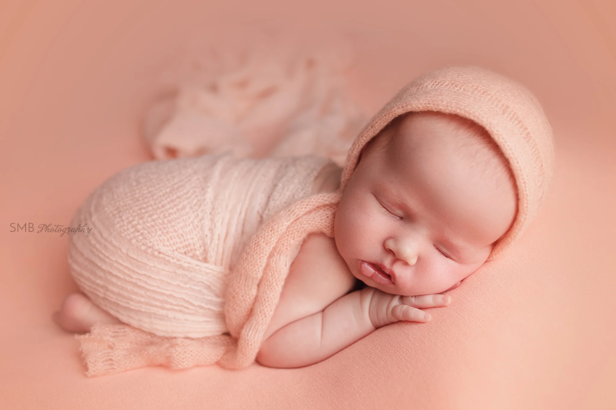 Newborn girl wrapped on peach blanket
