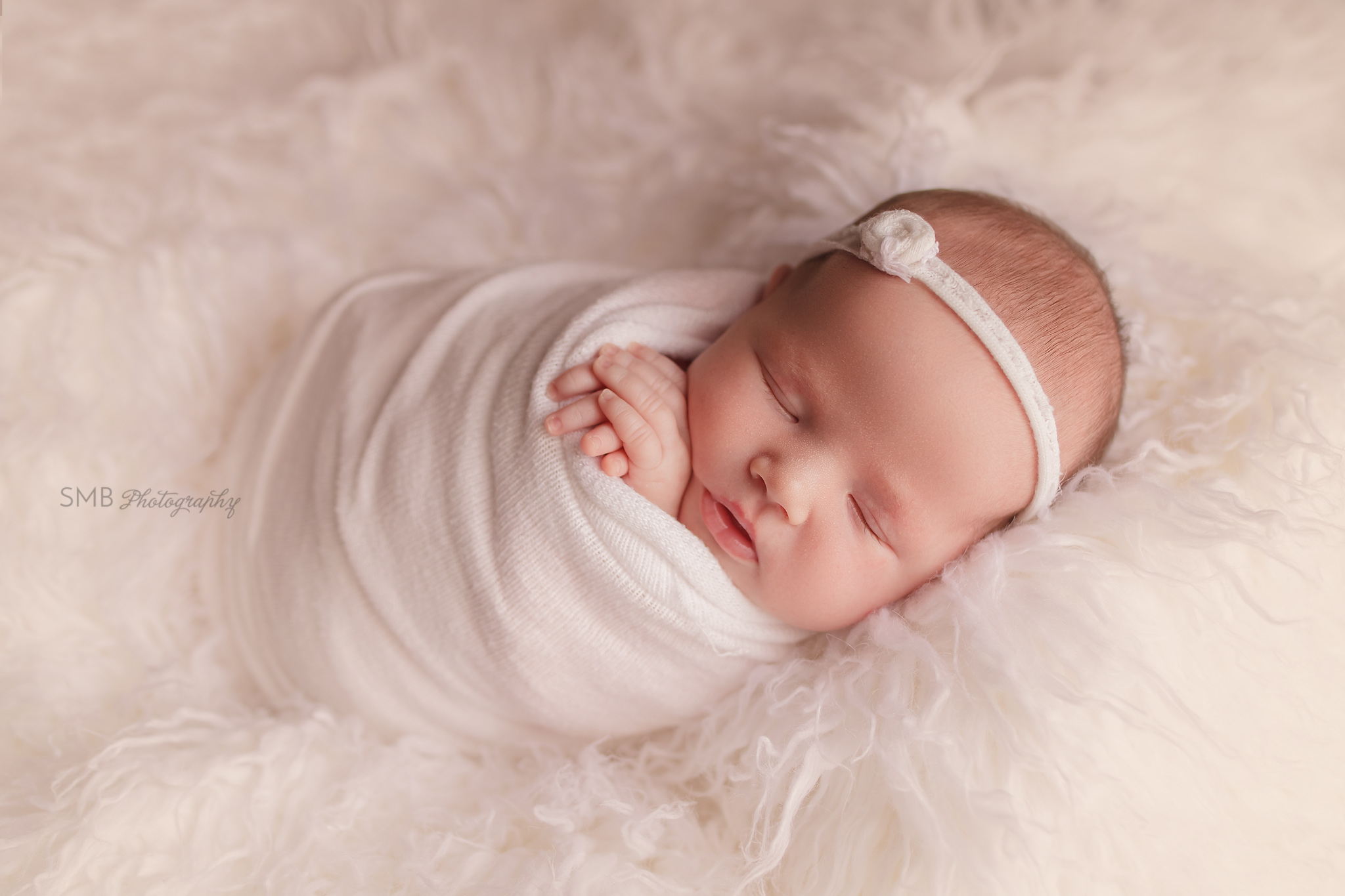Newborn girl sleeping on white flokati