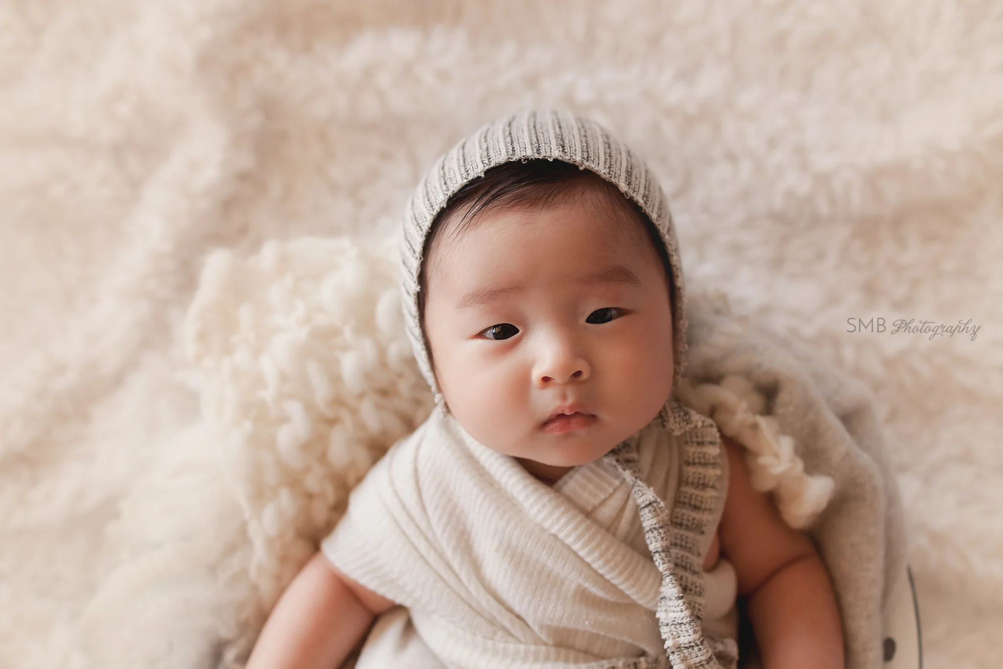 3 Month old baby boy wearing a bonnet laying in a bowl