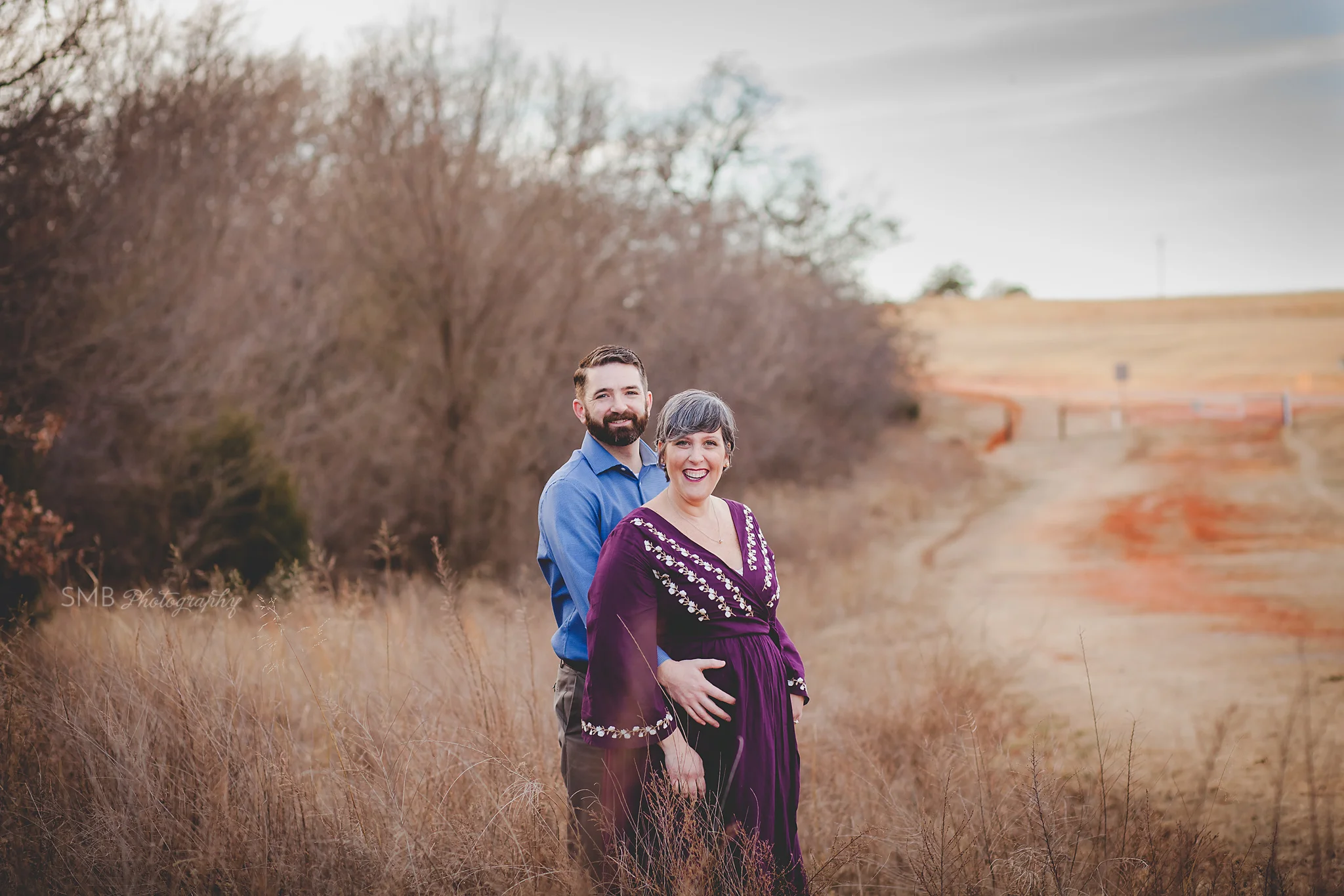 Mom and Dad smiling at camera standing in field