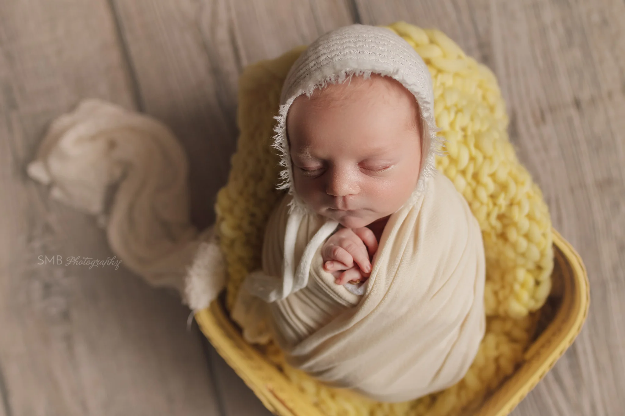 Newborn girl sleeping in vintage yellow sewing basket