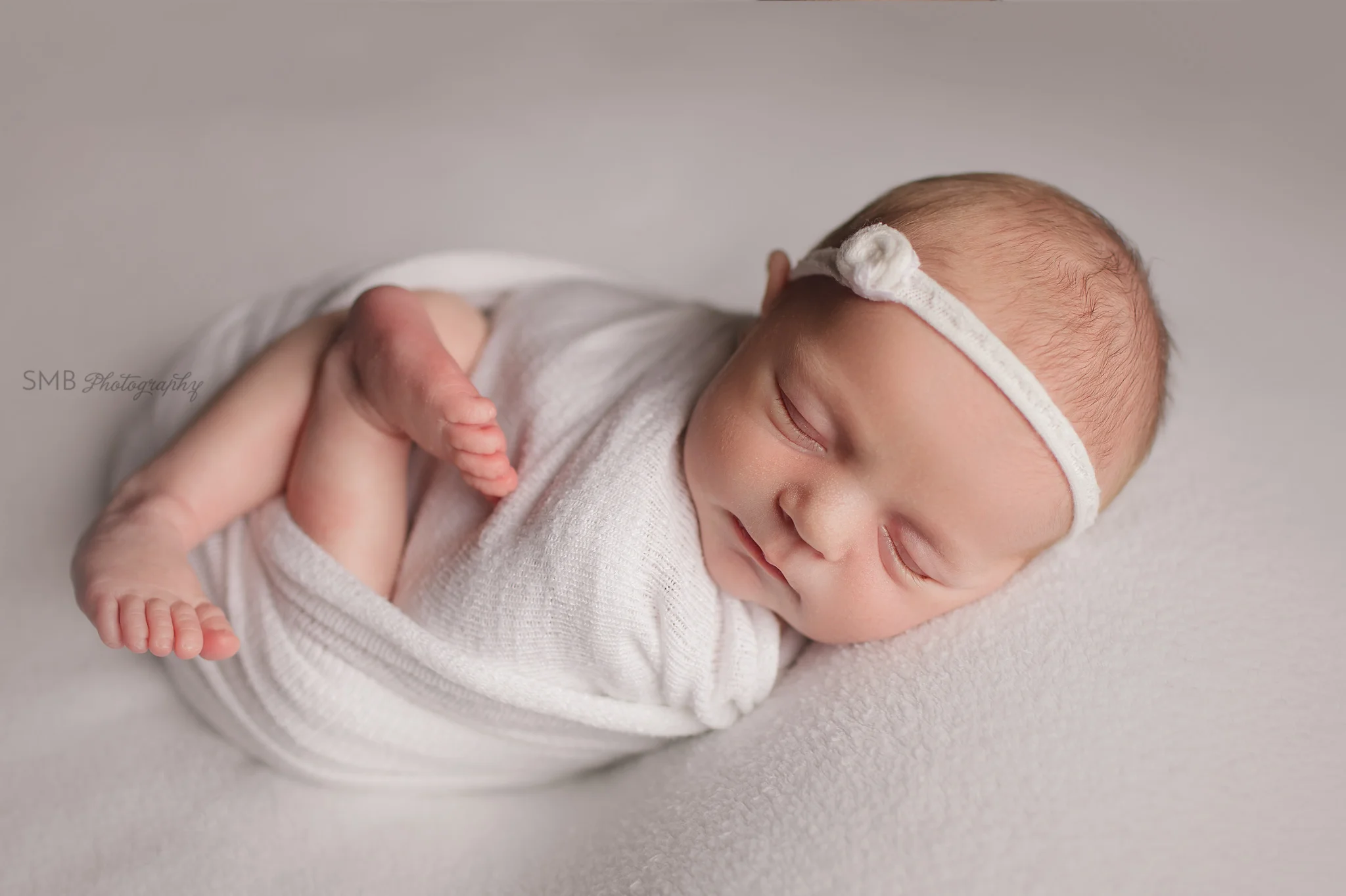 Newborn girl wrapped on ivory blanket