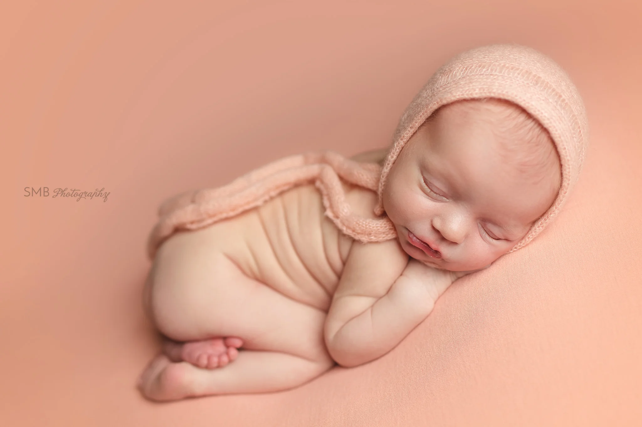 Newborn girl sleeping on peach blanket