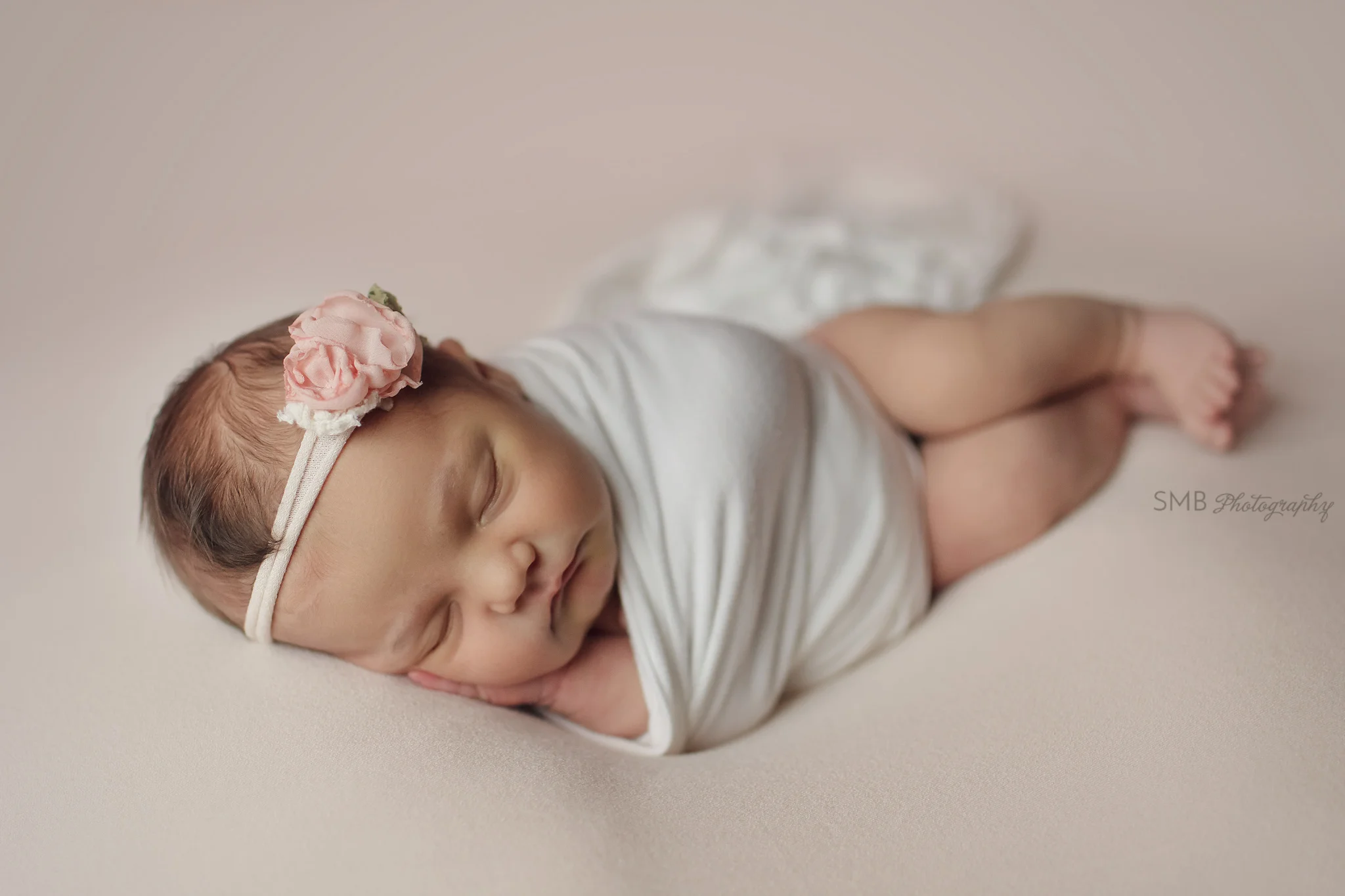 Newborn girl laying on side with hands under cheek