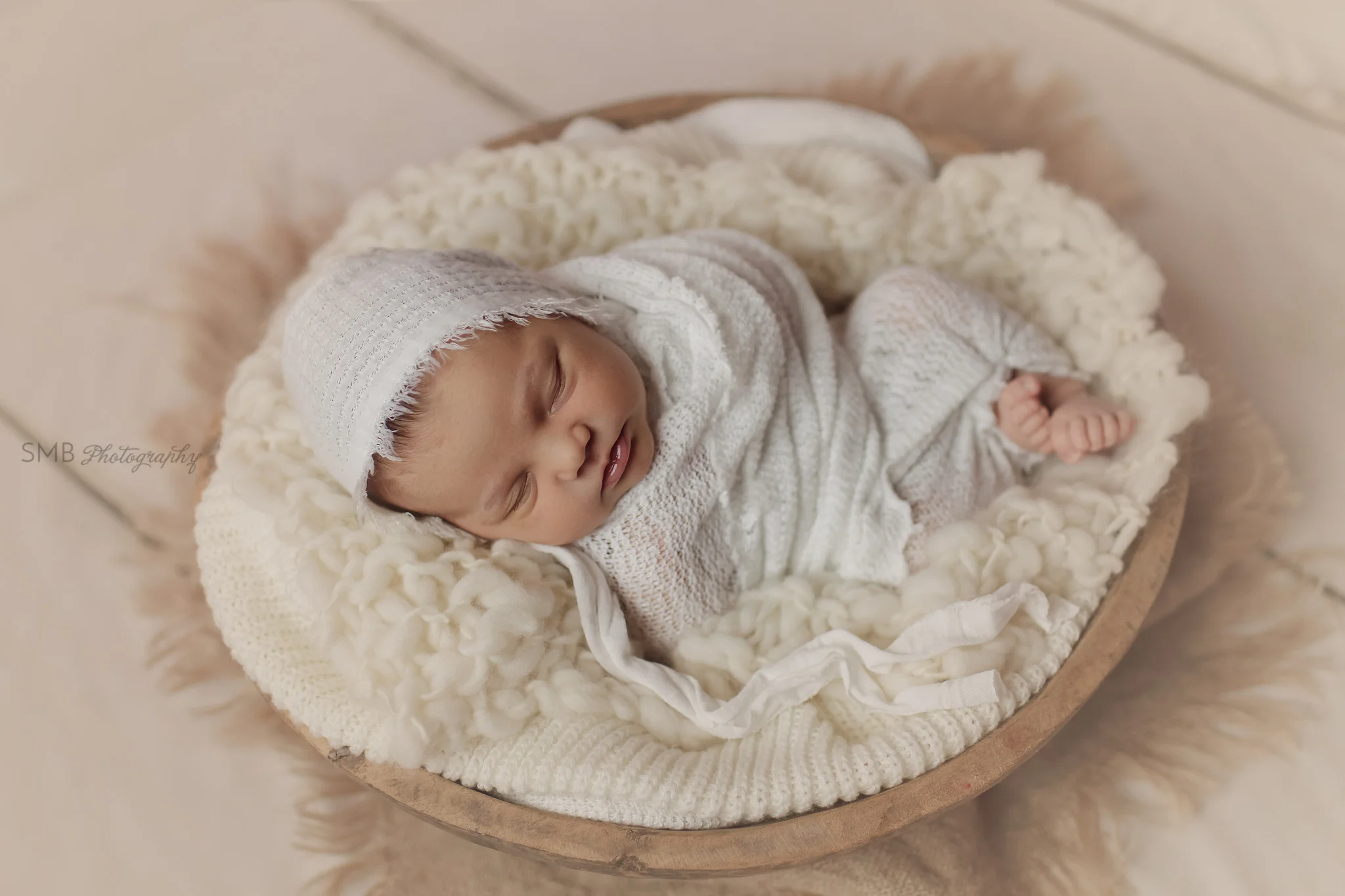 Baby wrapped in cream in a large wood bowl