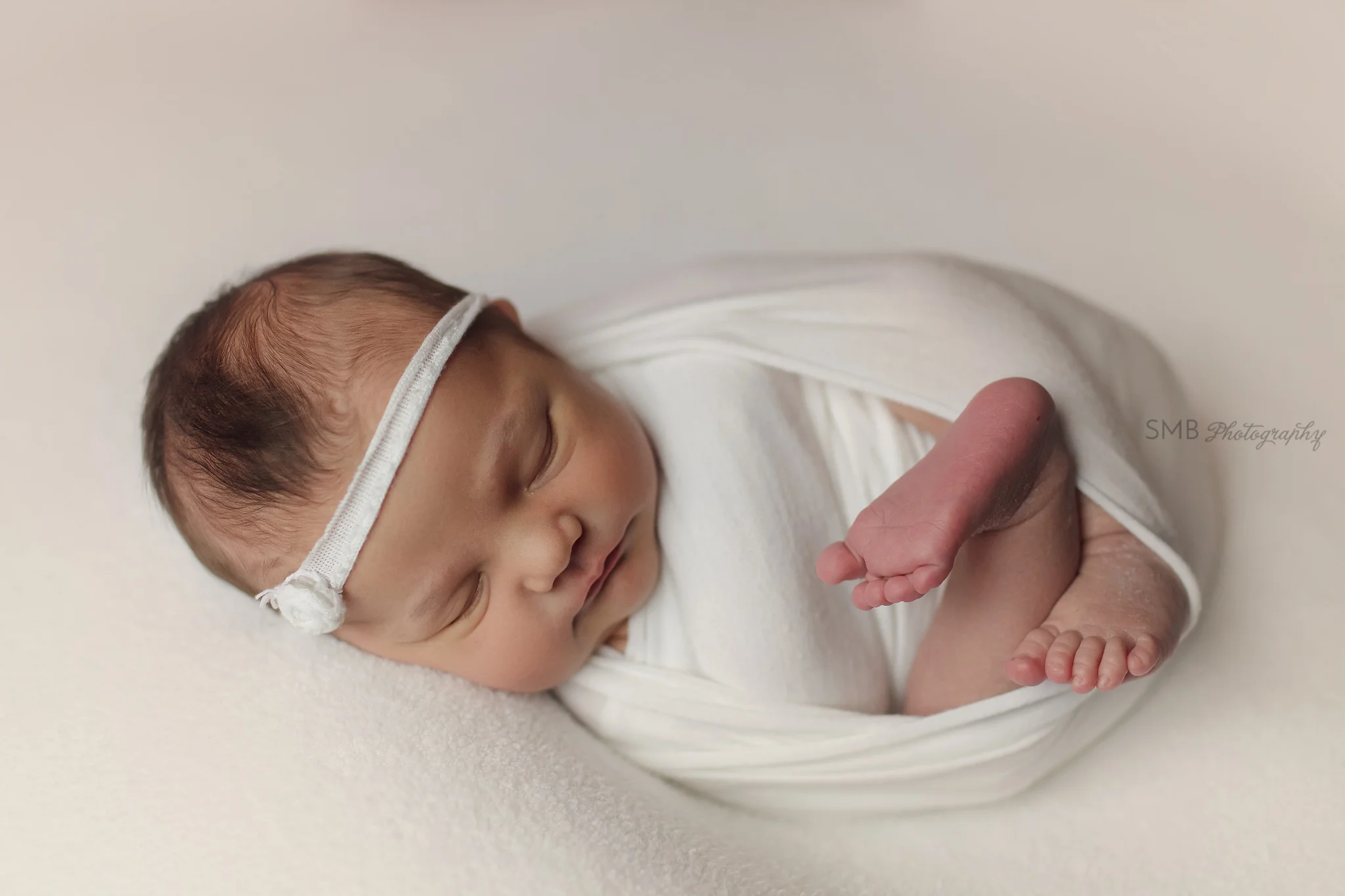 Baby wrapped on white fuzzy blanket