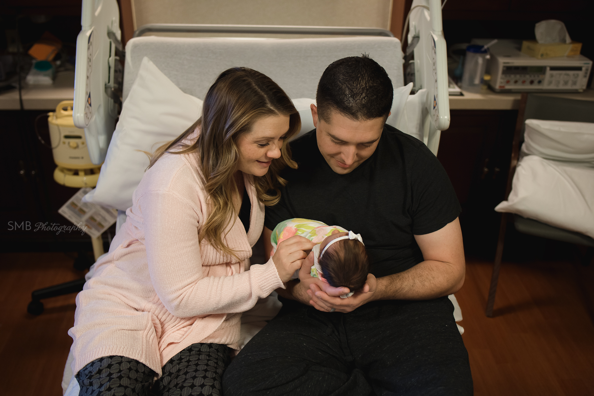 Mom and Dad smiling at newborn baby in hospital bed