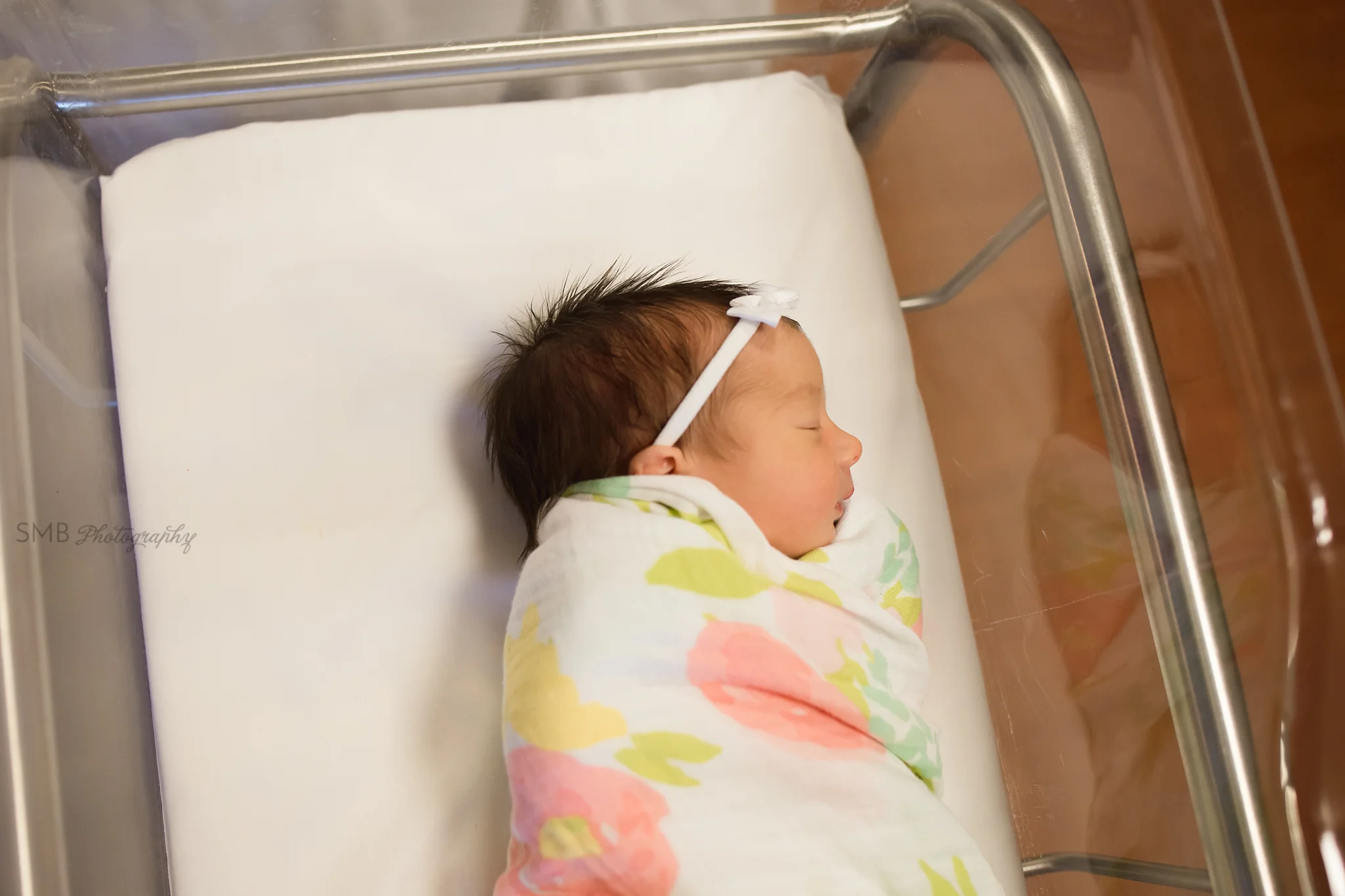 Baby girl wrapped in hospital bassinet