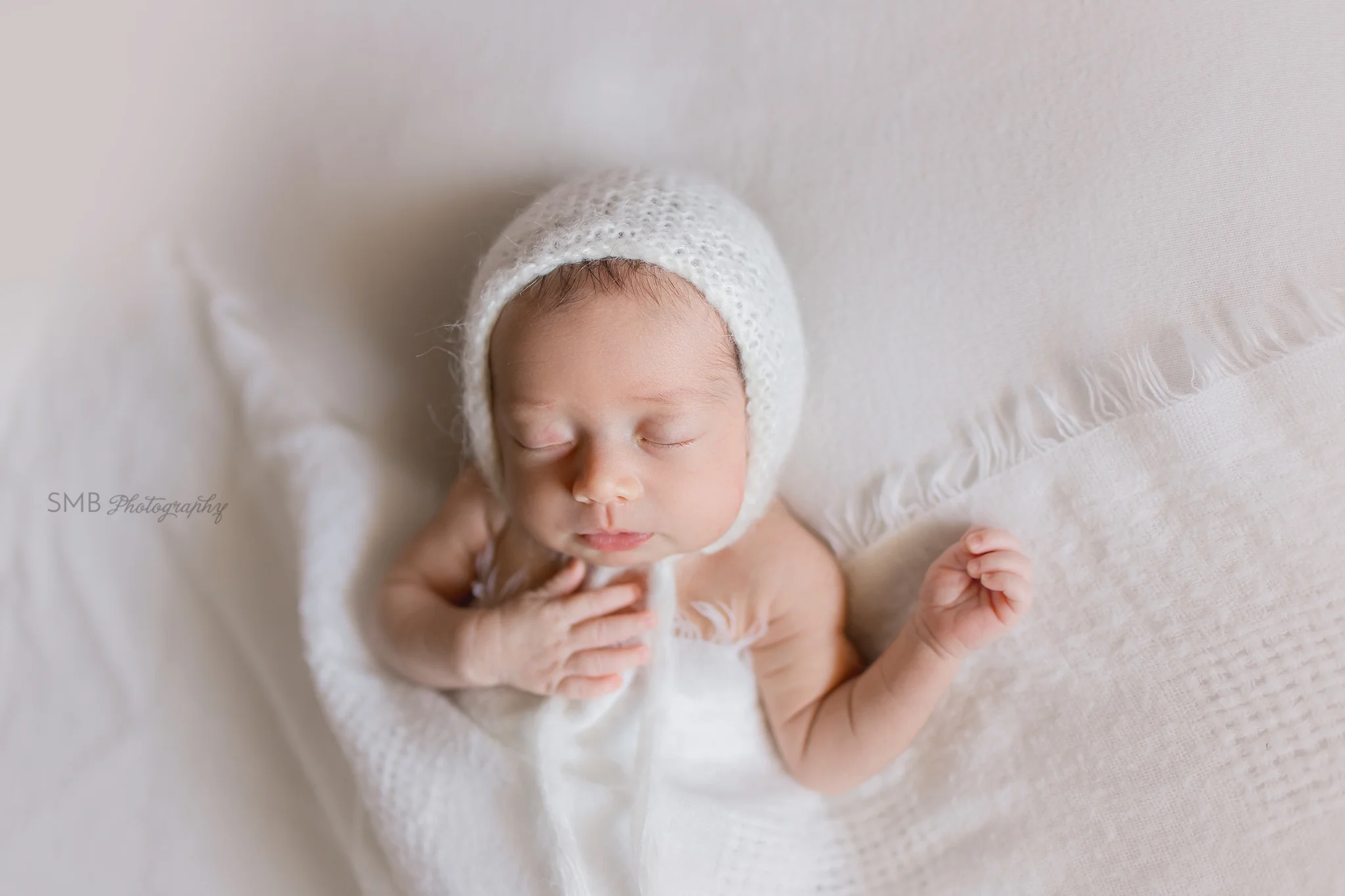 Newborn girl sleeping on white blanket