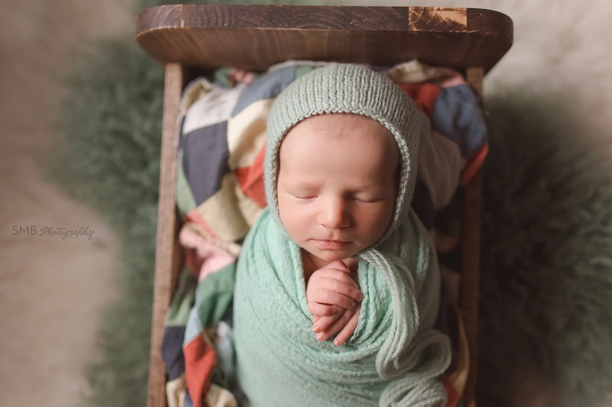 Newborn girl in bed on colorful patchwork quilt