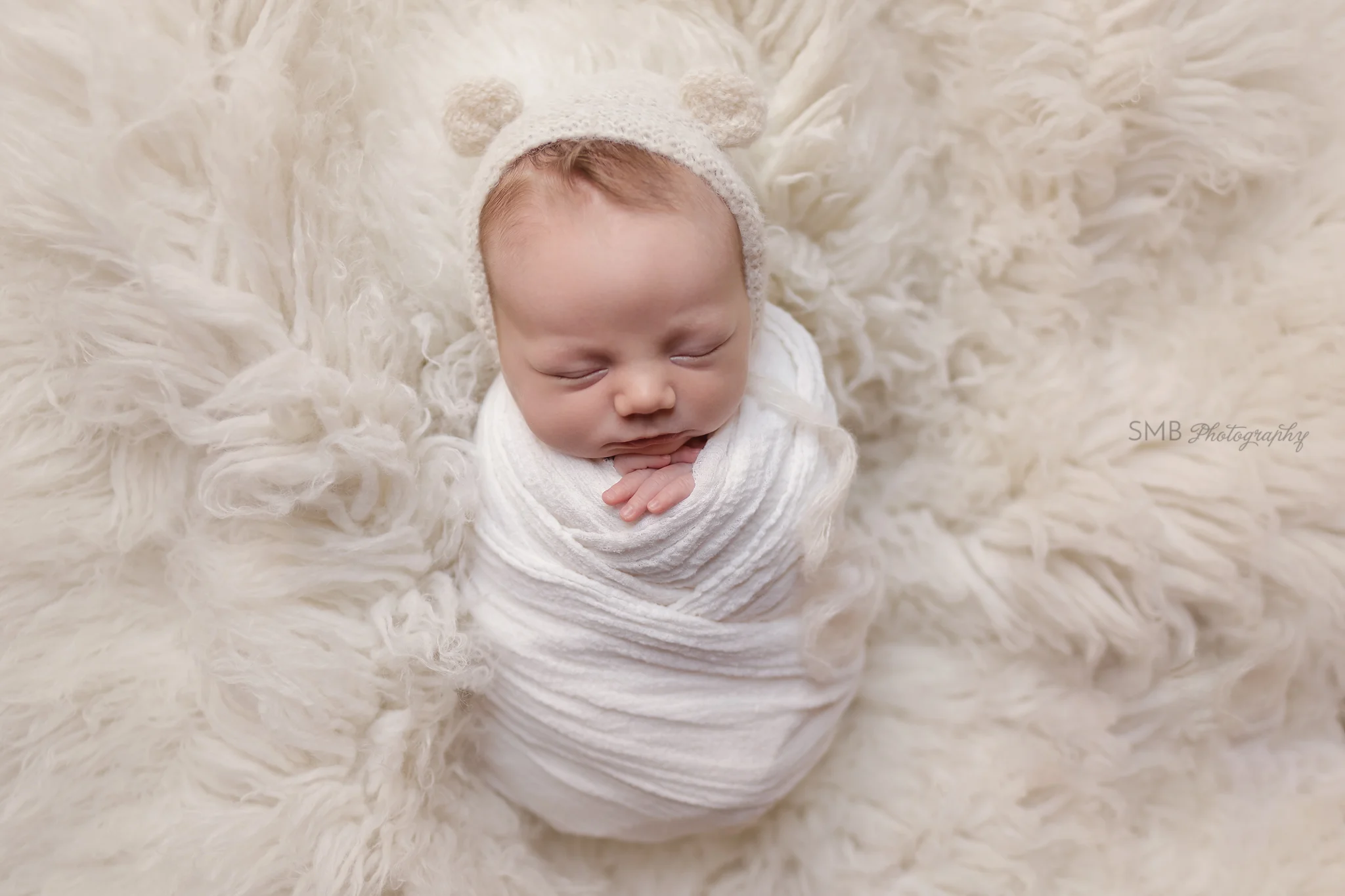 Baby boy wrapped on cream fur rug