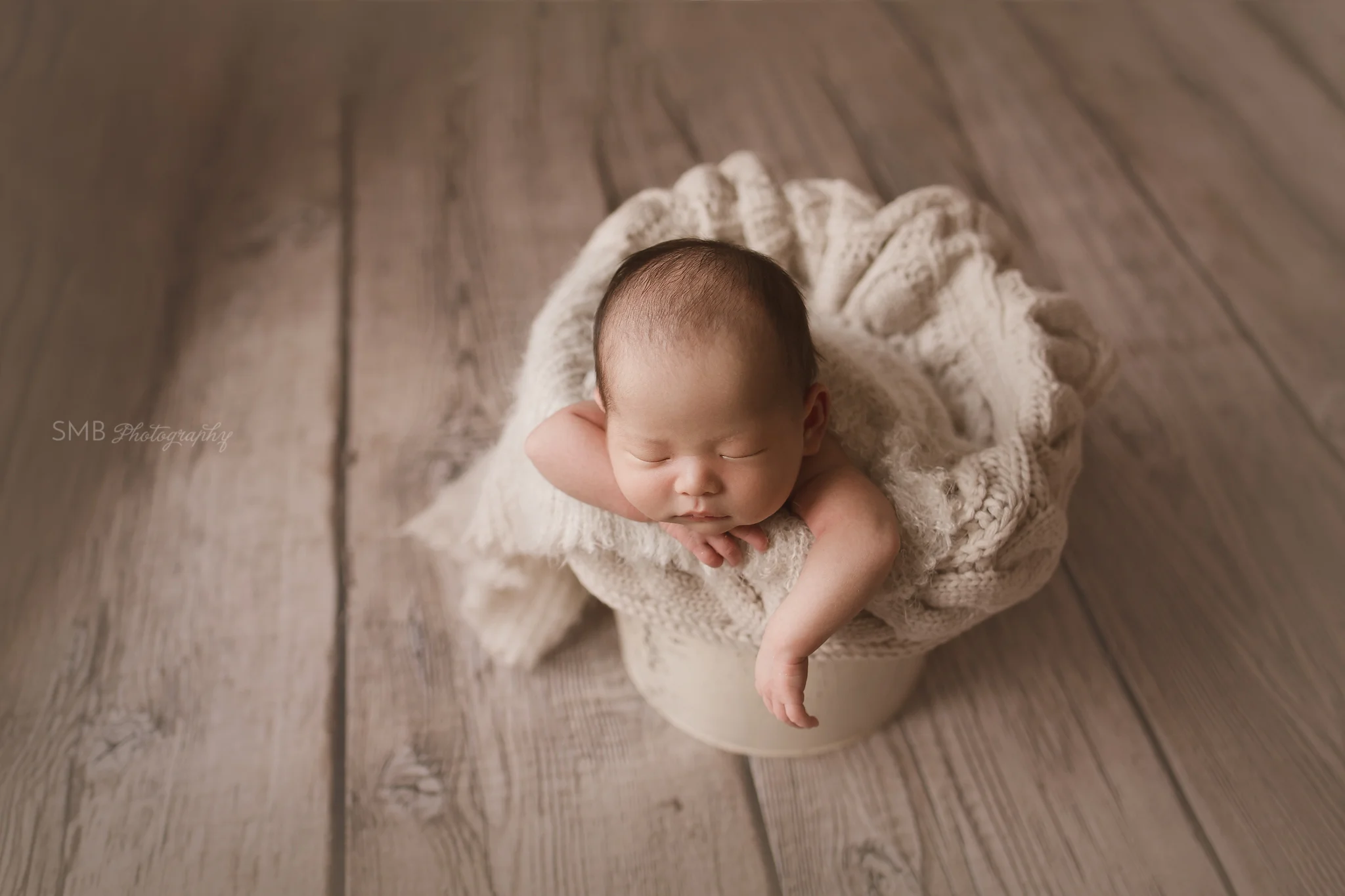 Newborn boy in cream colored bucket