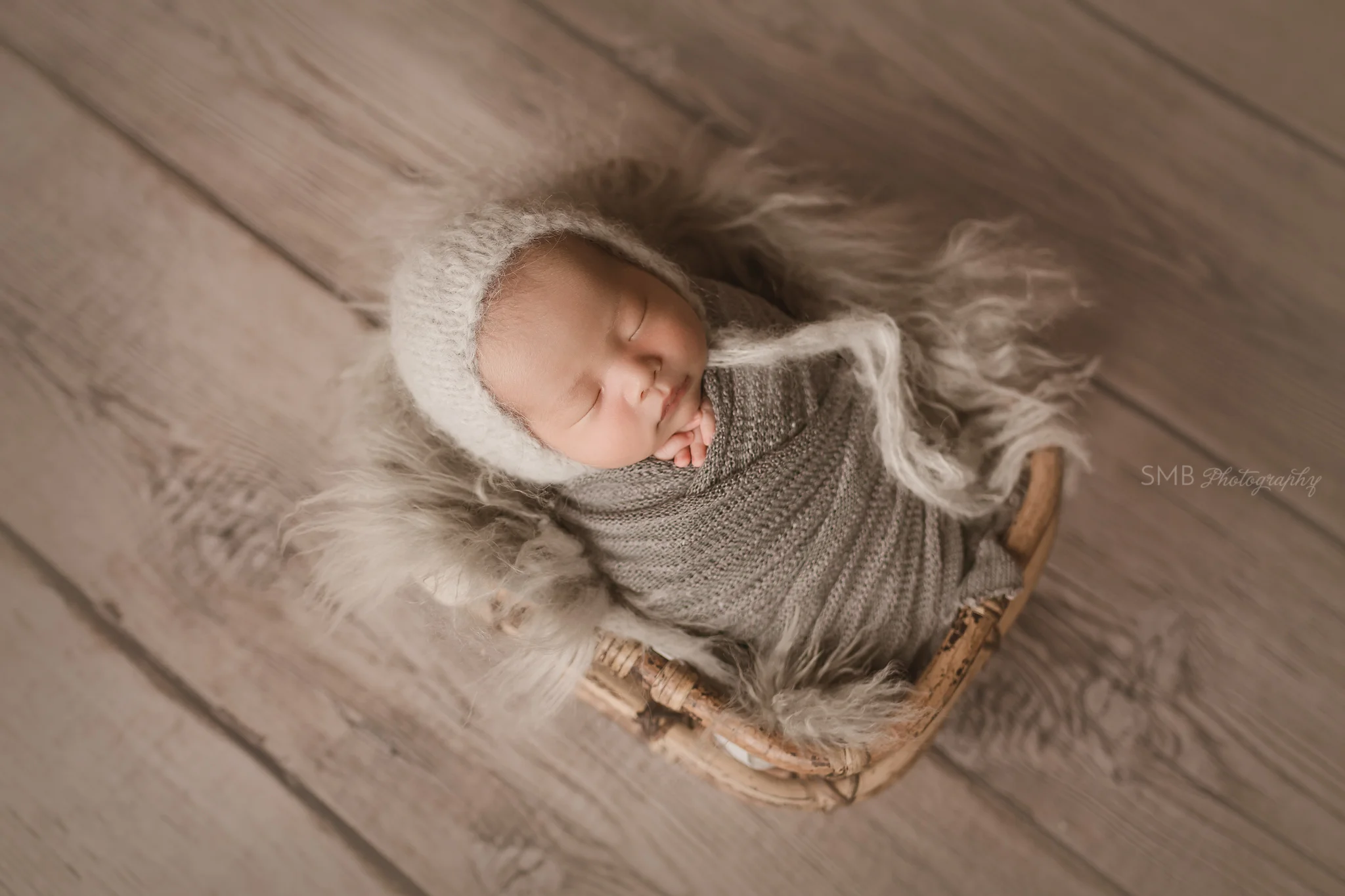Baby boy wrapped in charcoal gray in bamboo basket
