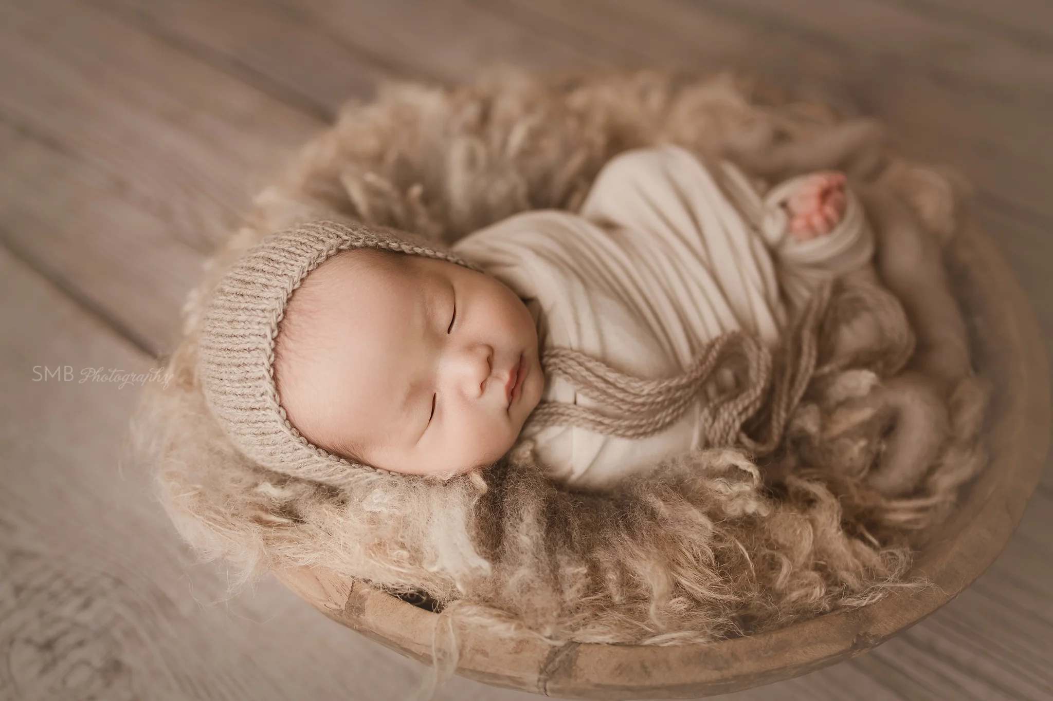 Newborn sleeping in large wood bowl